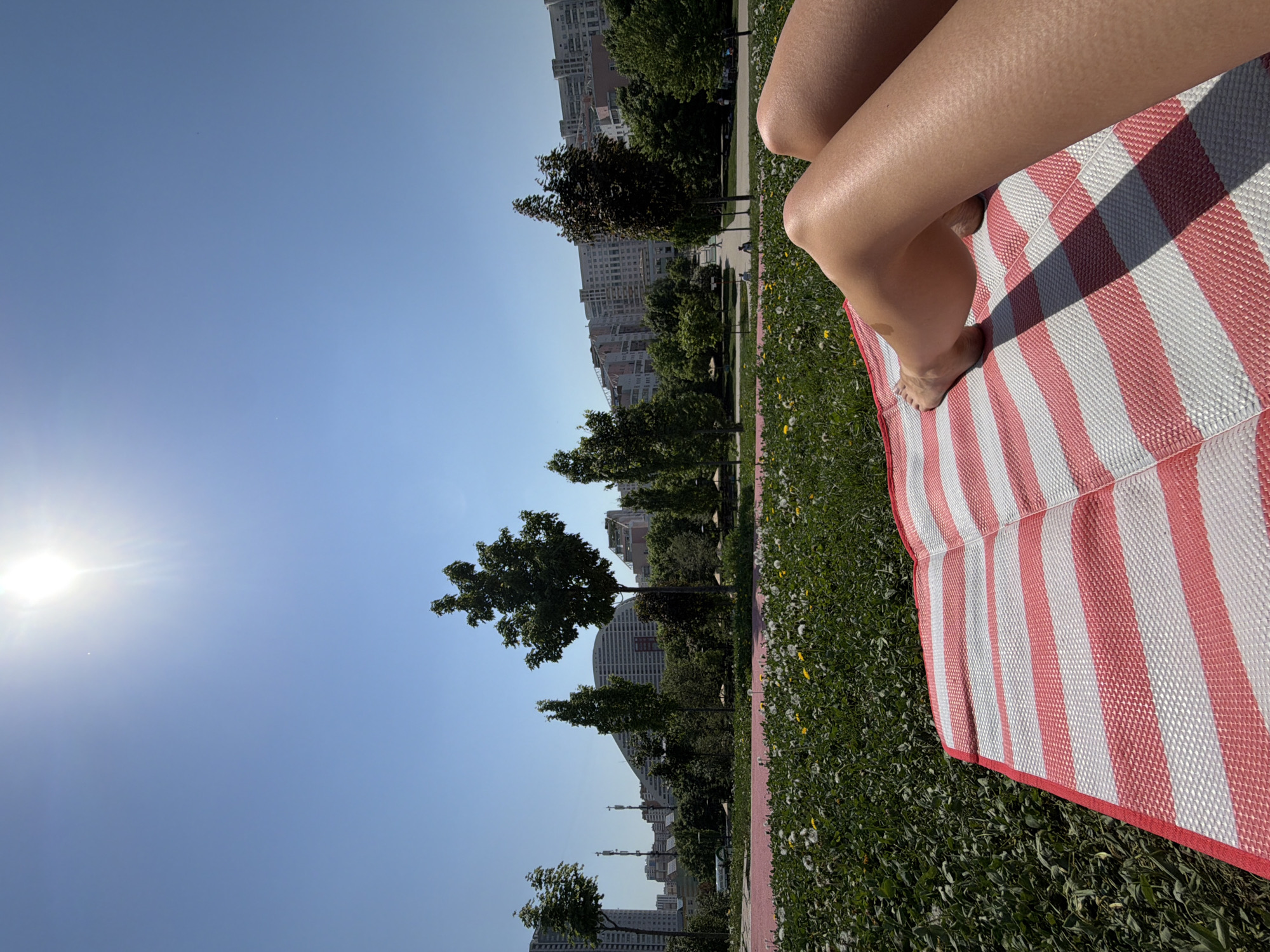 Person relaxes on striped mat in Moscow park