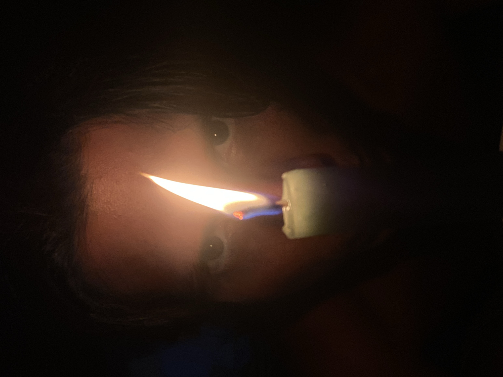 Person holds green candle in darkness in Venezuelan village