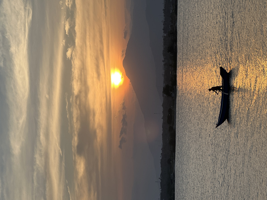 Sunset fishing boats and helmet-wearing individual documented in coastal Vietnam