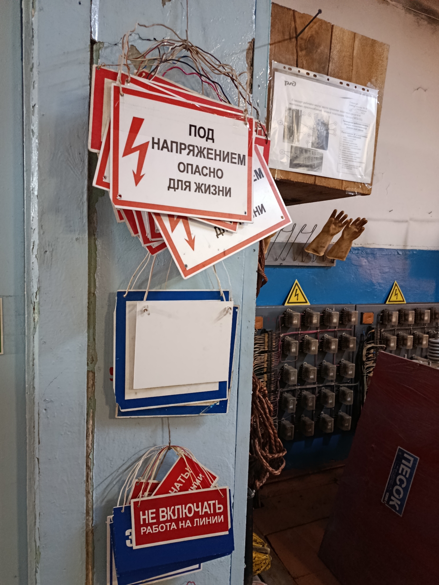 Warning signs line a weathered wall in a Russian utility space.