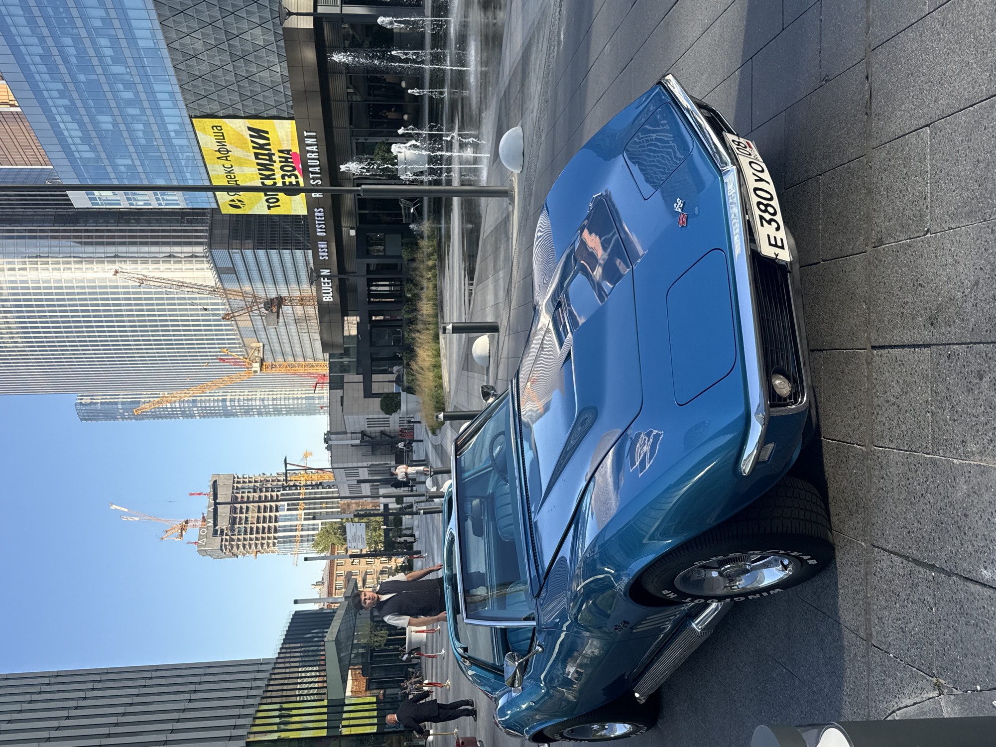 Classic blue Corvette Stingray parked outside modern Khimki building