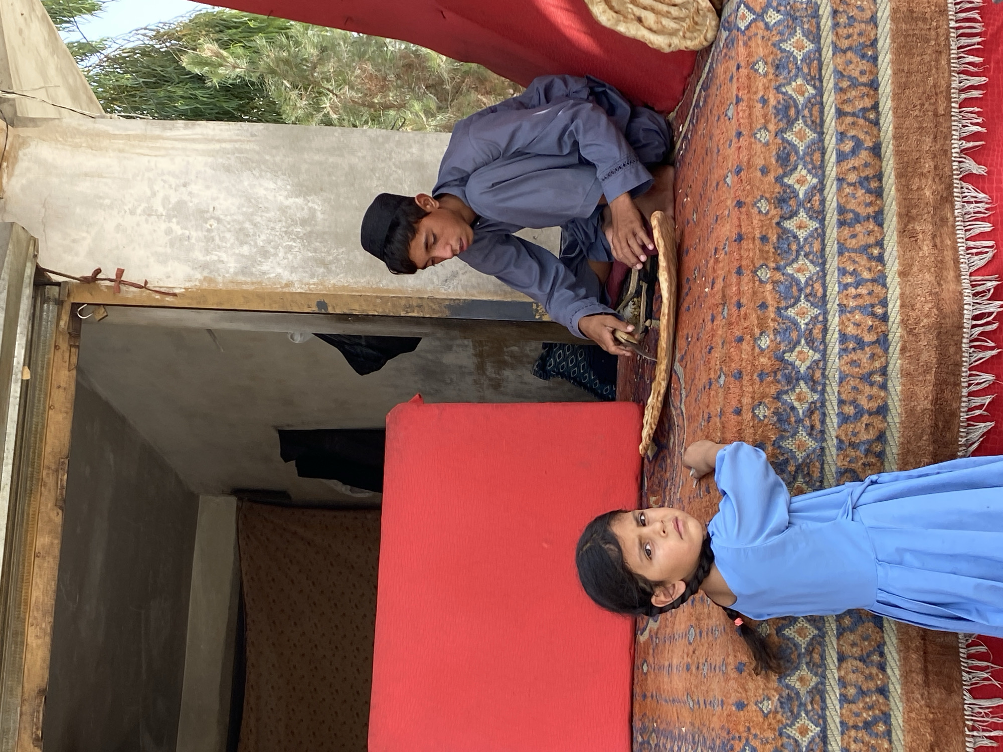 Flatbread being sliced on a colorful rug in Kandahar