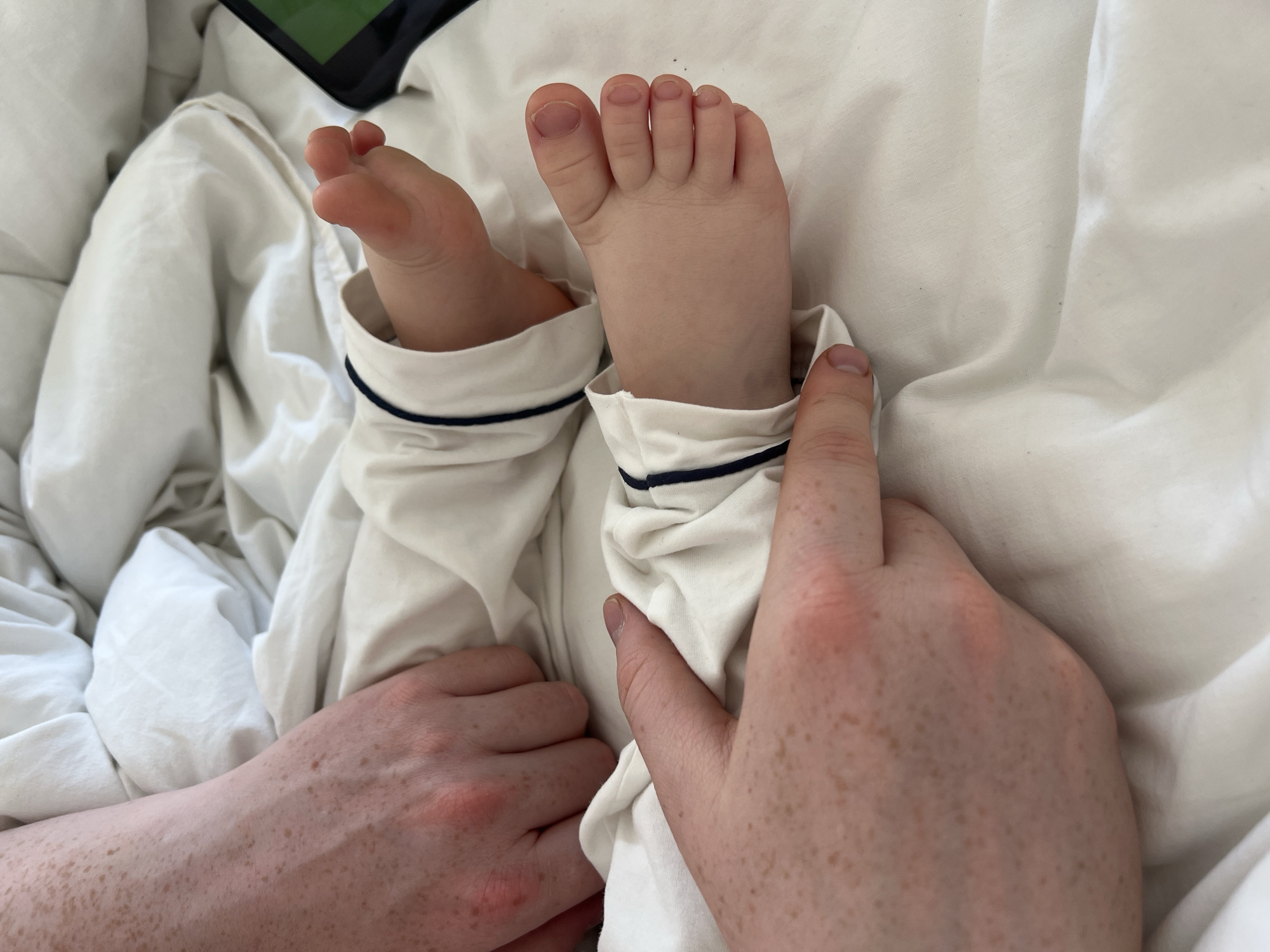 Adult tends to infant in white pajamas, Russia