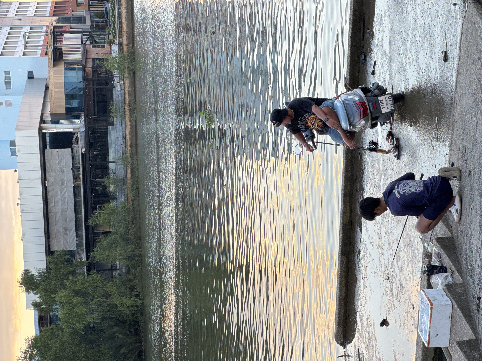 Fishing and moored boats along Surat Thani's riverside at dusk