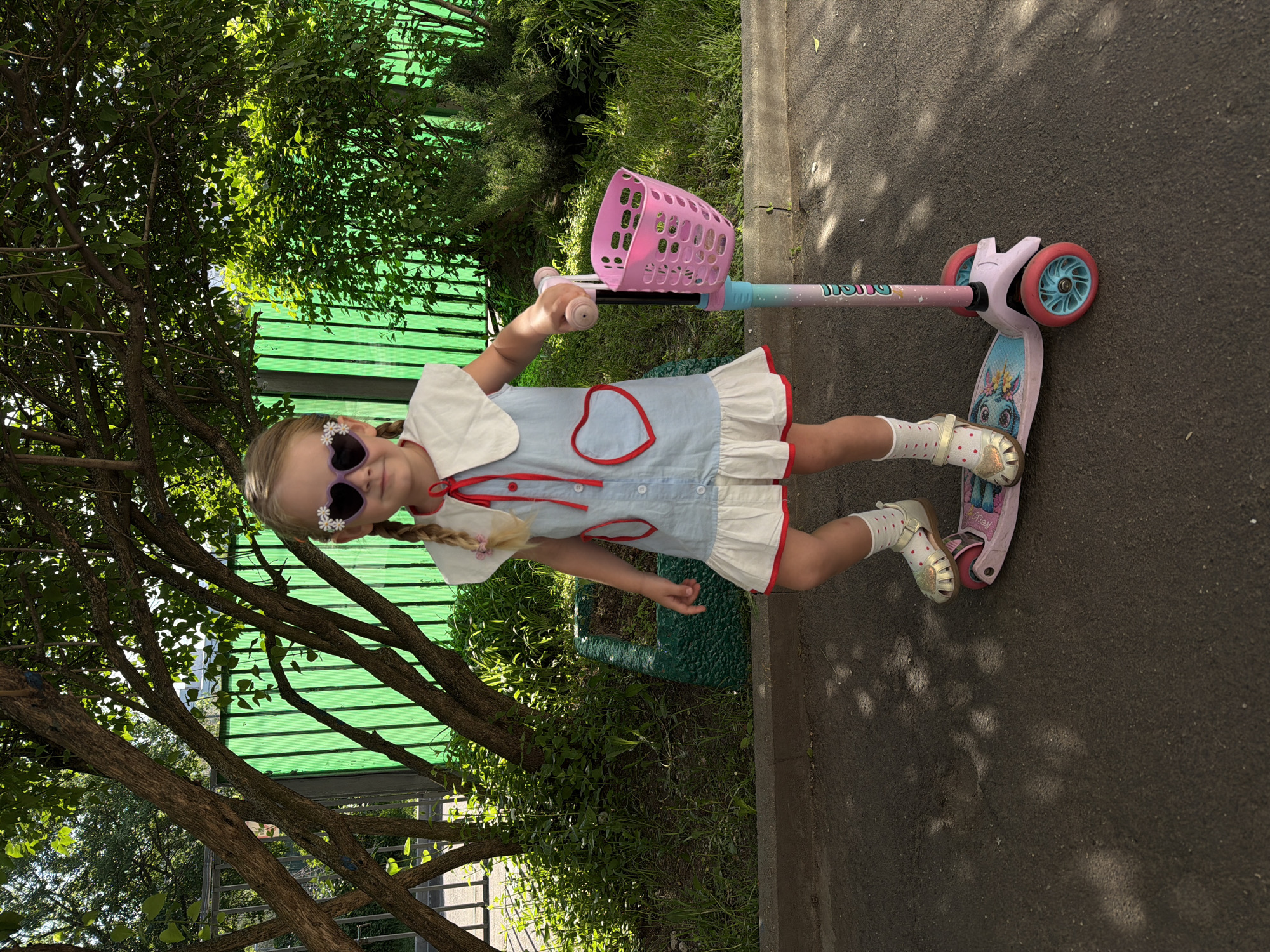 Girl with decorated sunglasses rides pink-basket scooter in Moscow