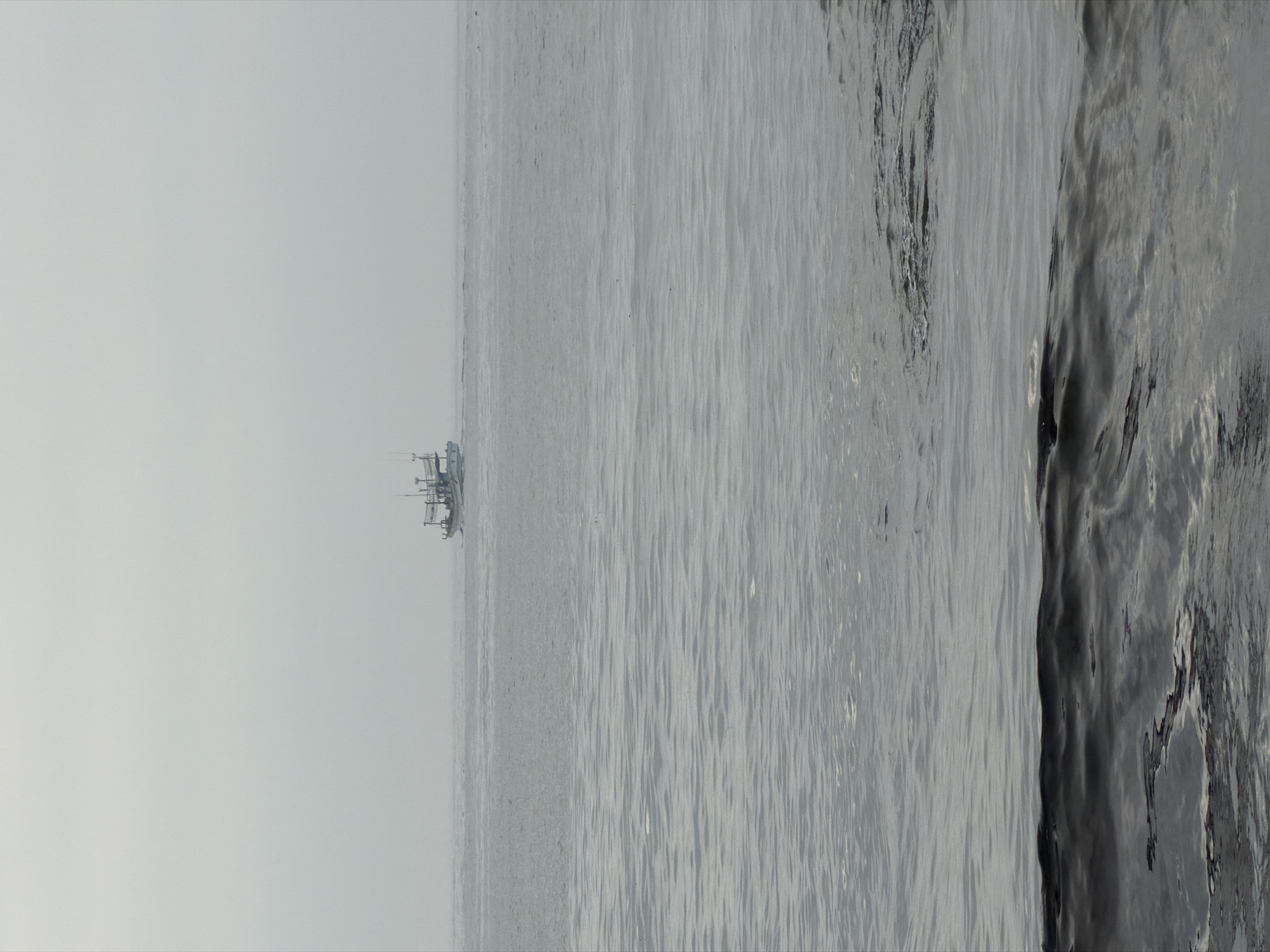 Fishing boat cuts through calm gray waters off Jeju