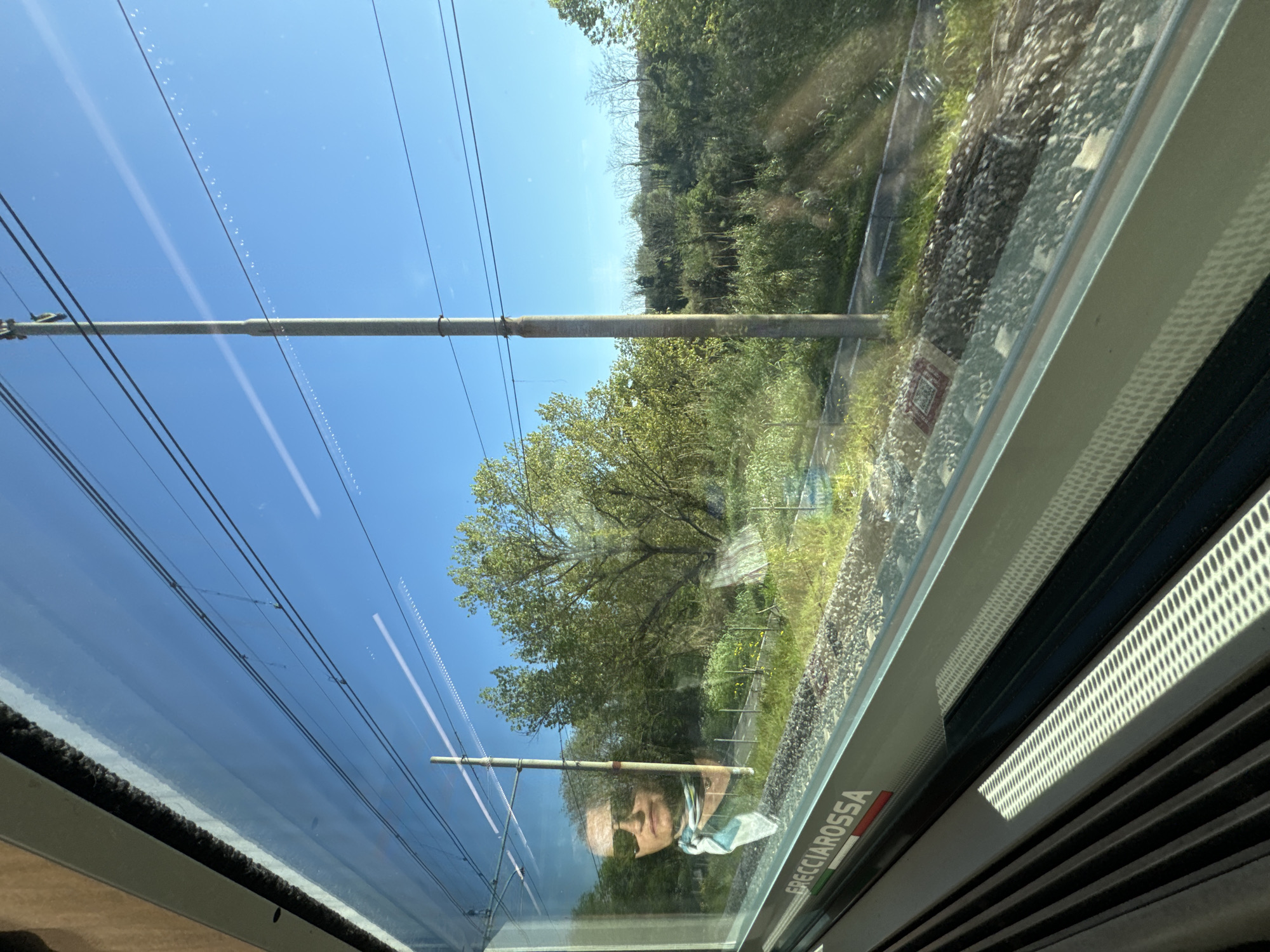Masked passenger travels through Rome countryside by train