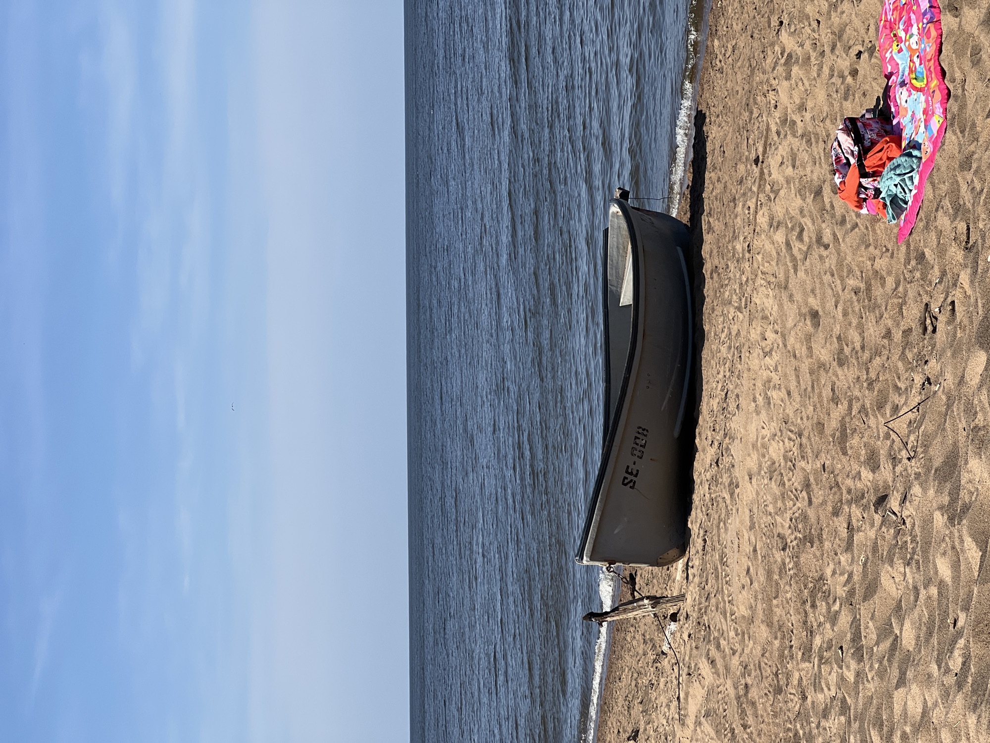 Quiet morning on the beach, rowboat ashore, feet in the surf