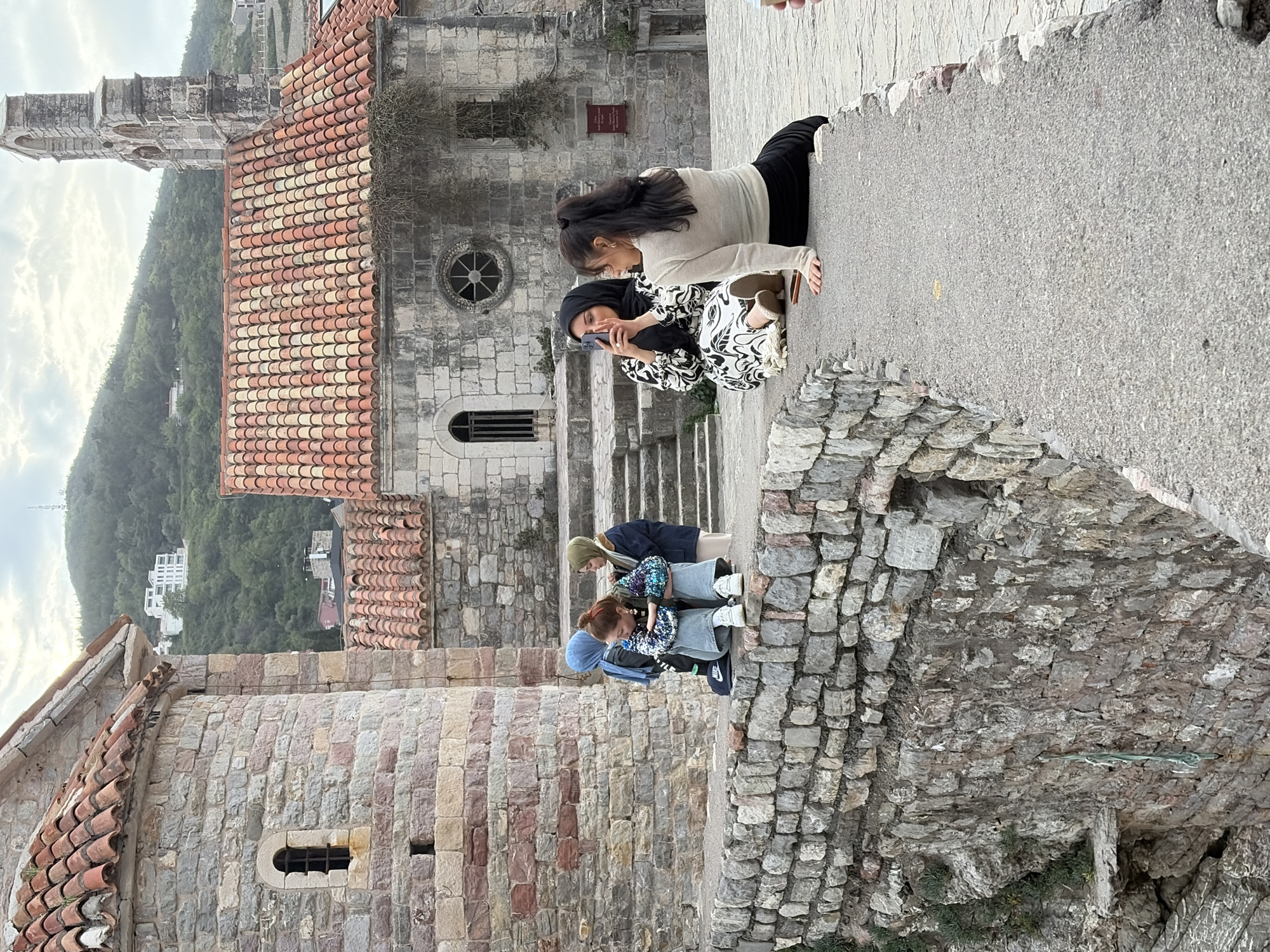 Women photograph on stone walkway in Budva with children nearby