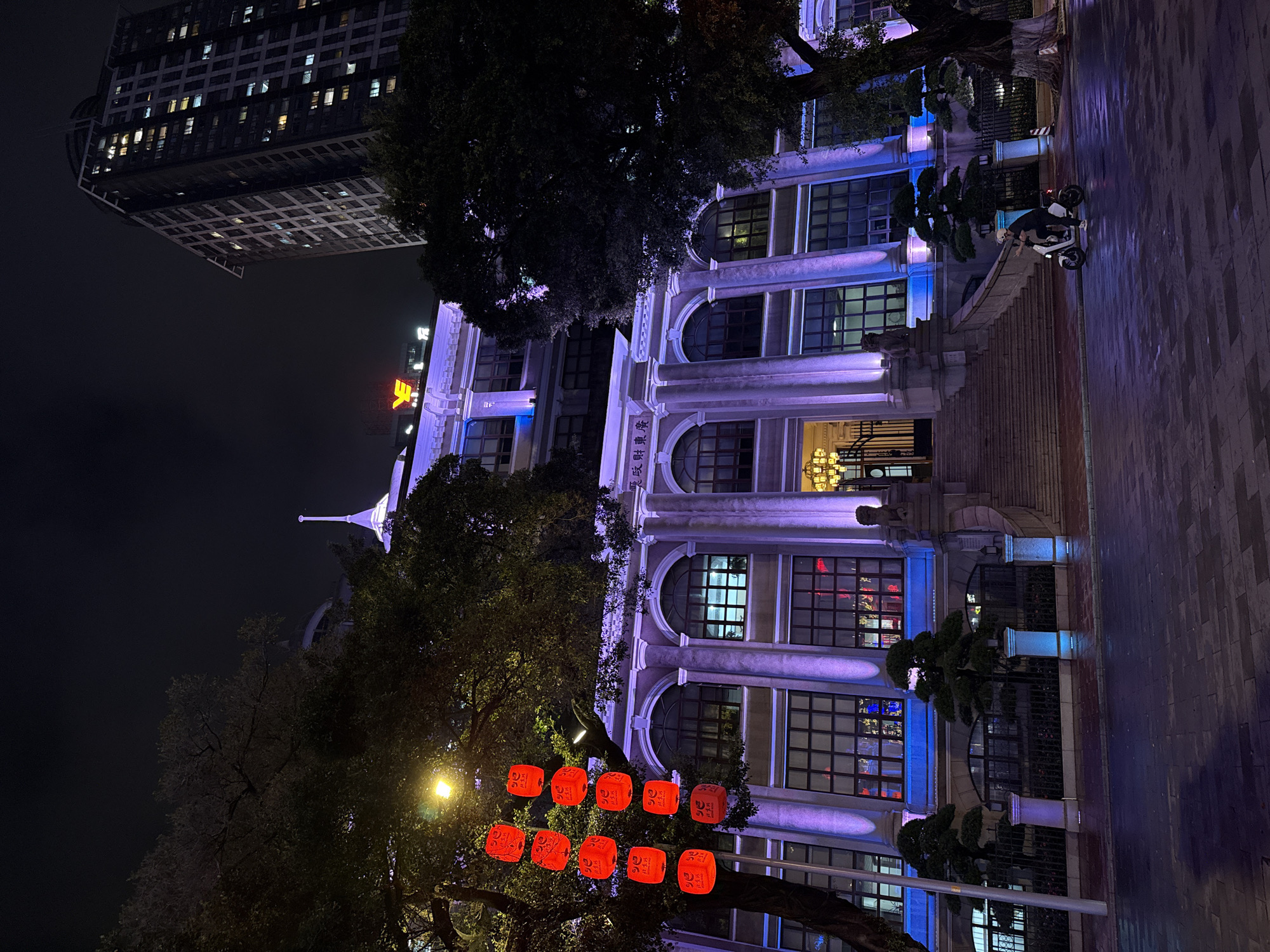 Woman walks illuminated street in Yuexiu District at night