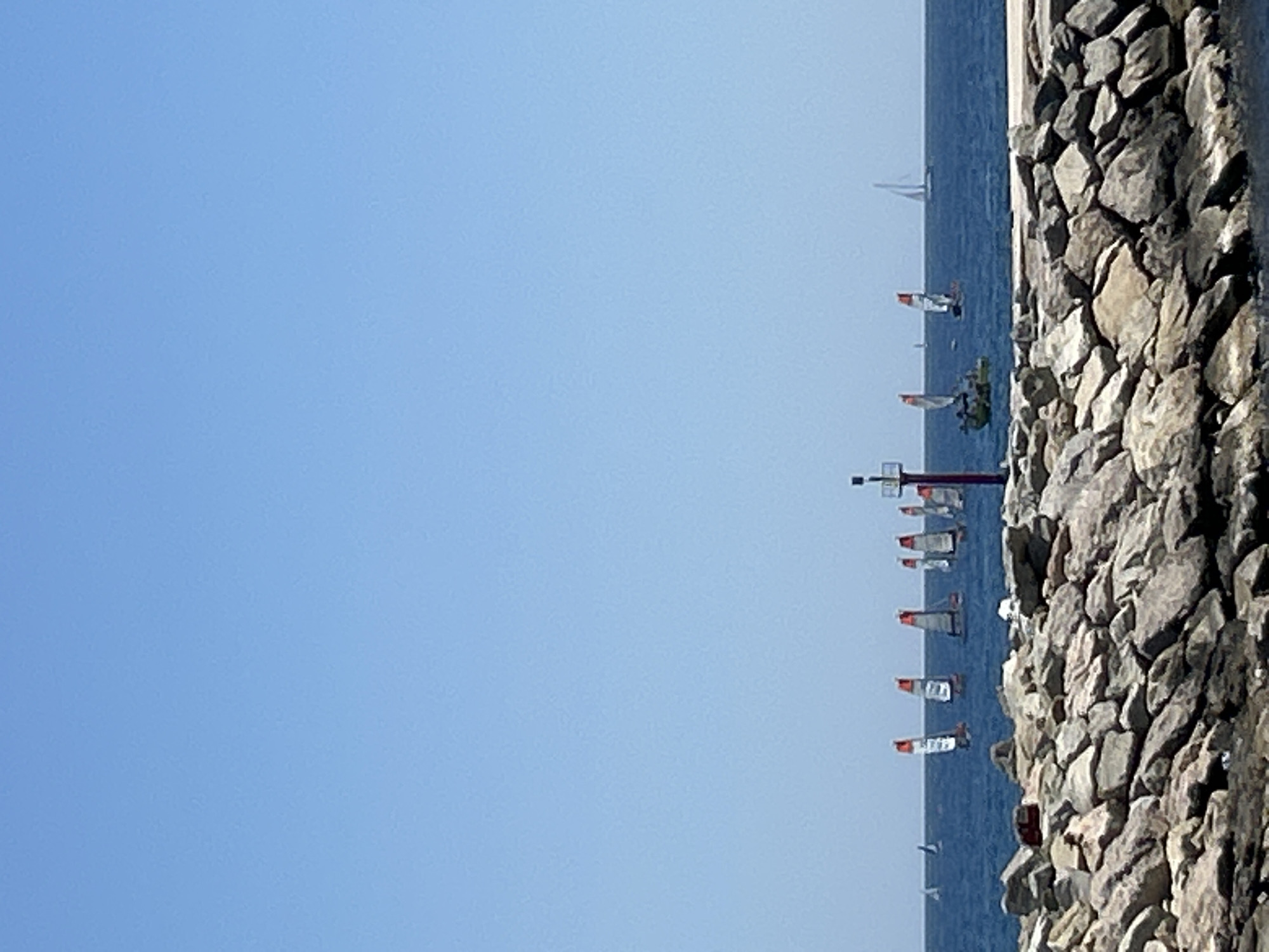 Barcelona waterfront: calm sea, sailboat, skyline on a clear morning