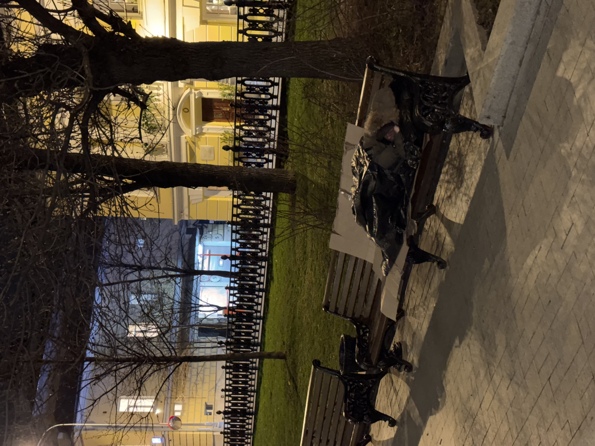 Person sleeps on Moscow park bench covered by tarp