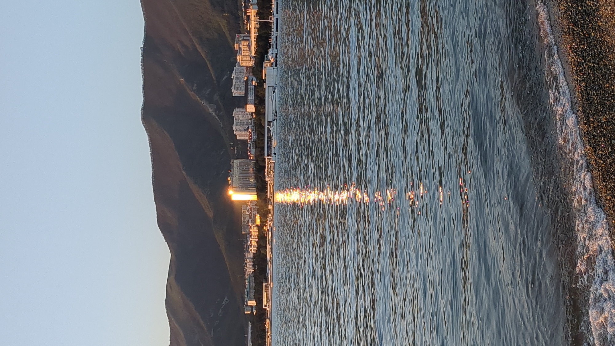 Witness documents peaceful sunset over water from rocky shore