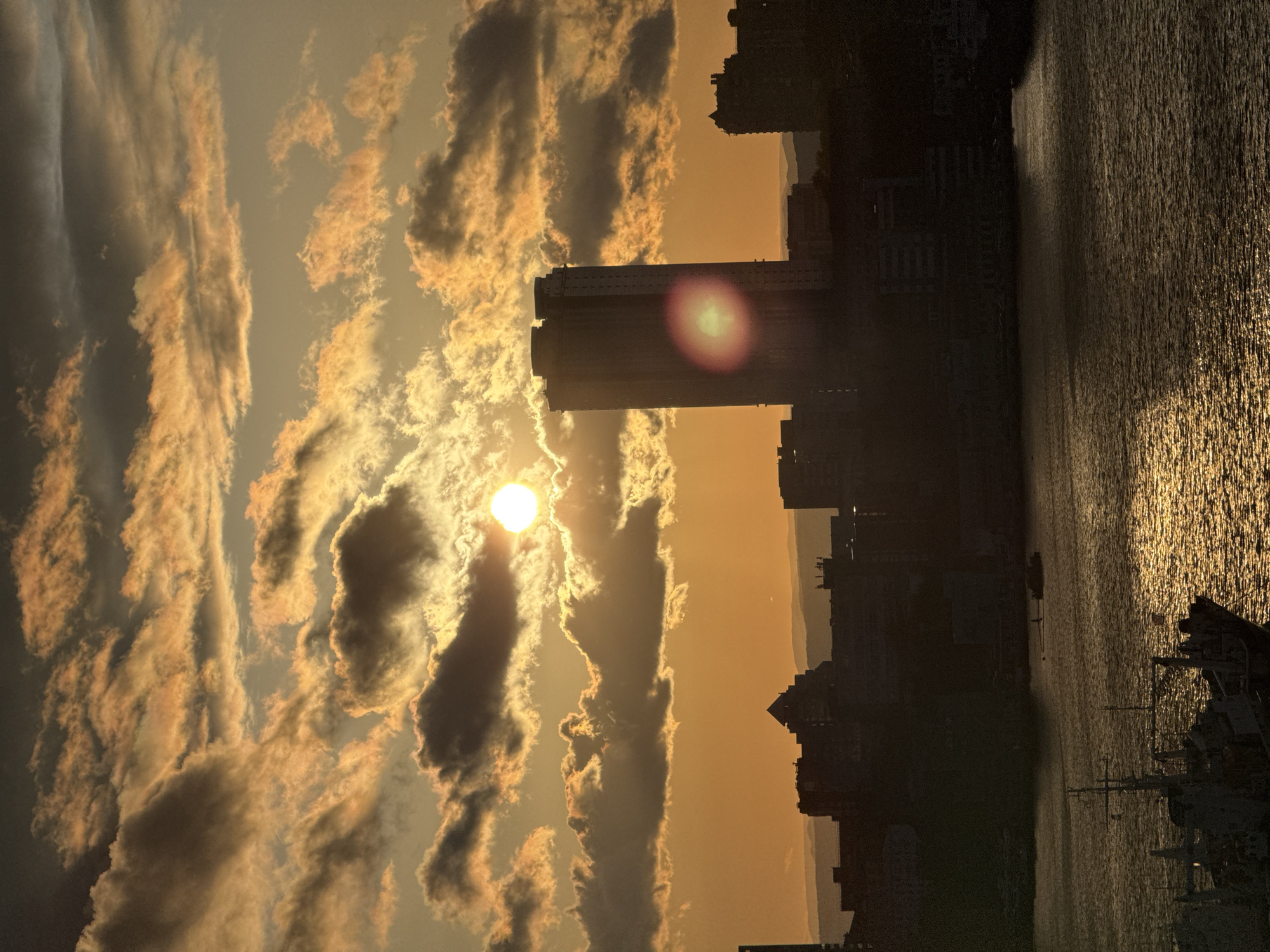 Golden sunrise illuminates cloudy skies over Vladivostok cityscape