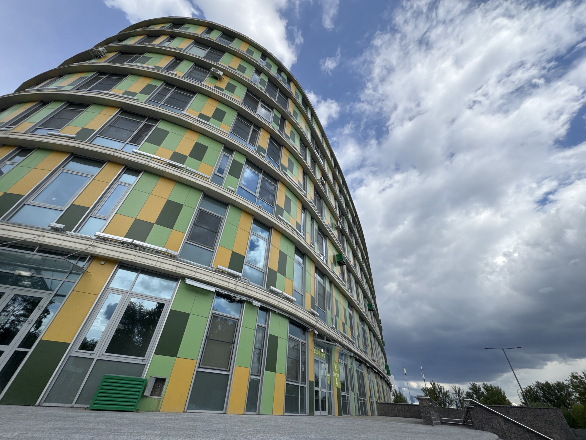 Modern curved building with colorful geometric panels observed