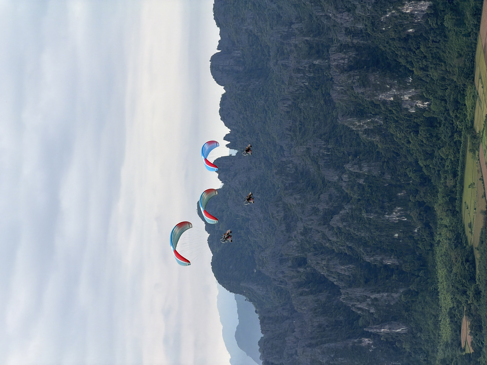 Paragliders with colorful wings over Laos mountain landscape