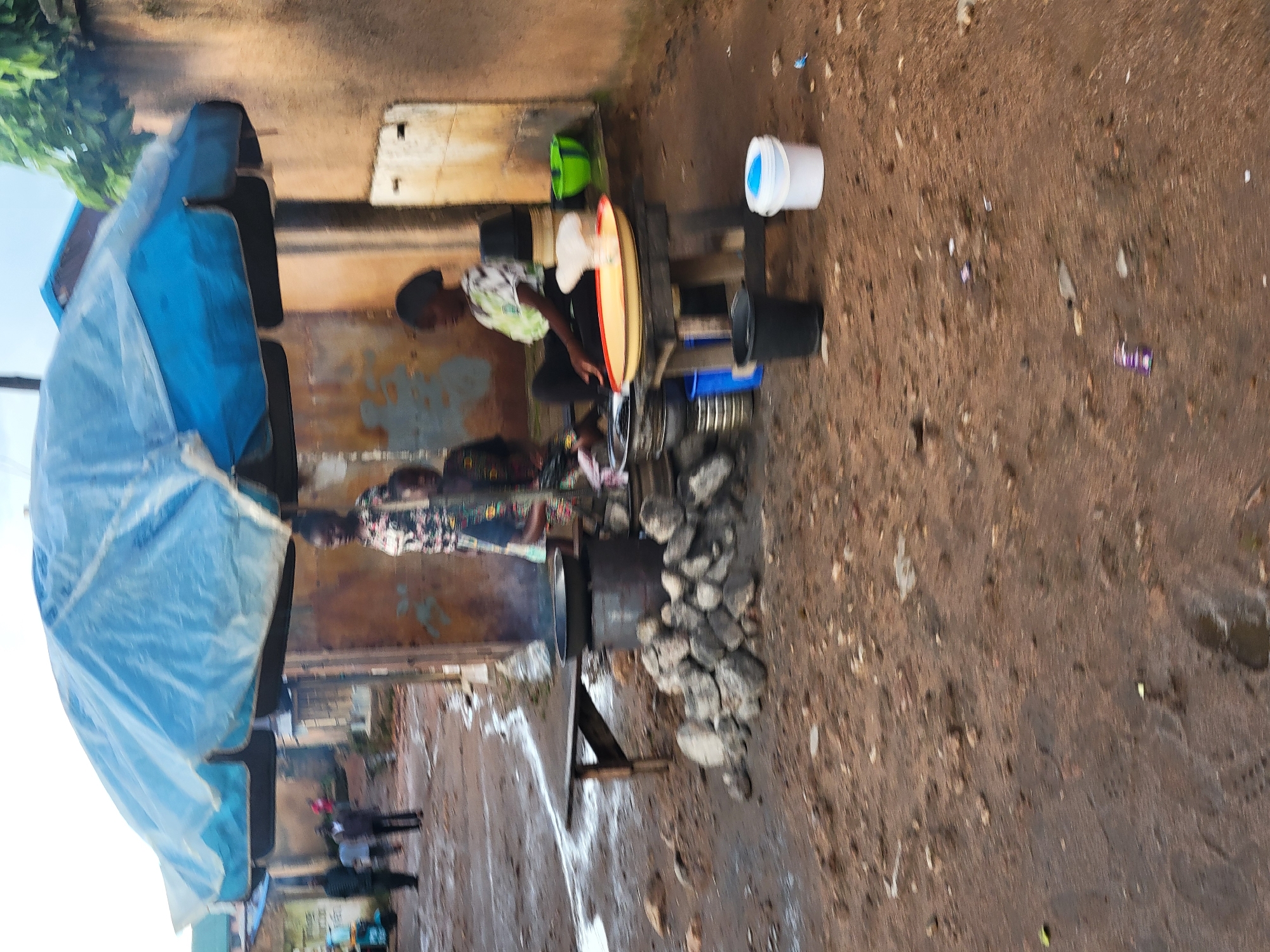 Everyday street life around a village food stall and dirt roads.