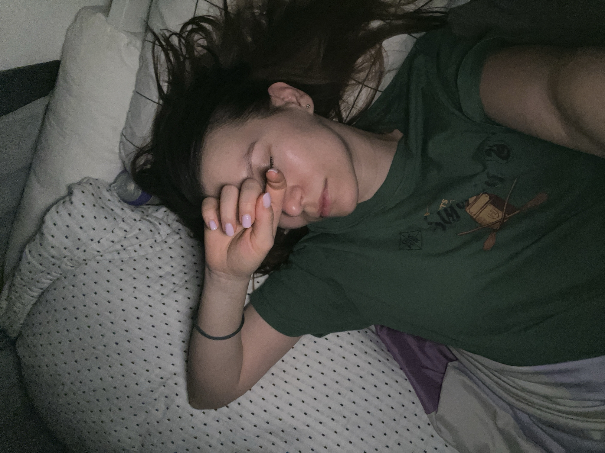 Woman rests in bed wearing Slytherin shirt in Limassol