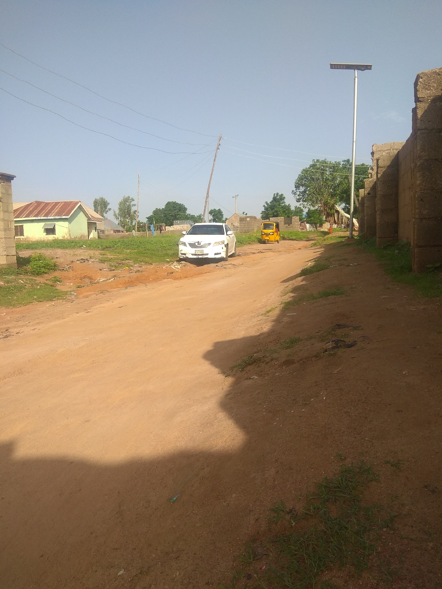 Morning foot traffic on a dusty residential street in Jalingo