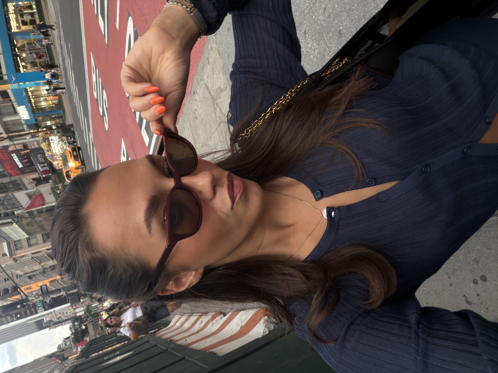 Woman adjusts sunglasses during dramatic New York sunset