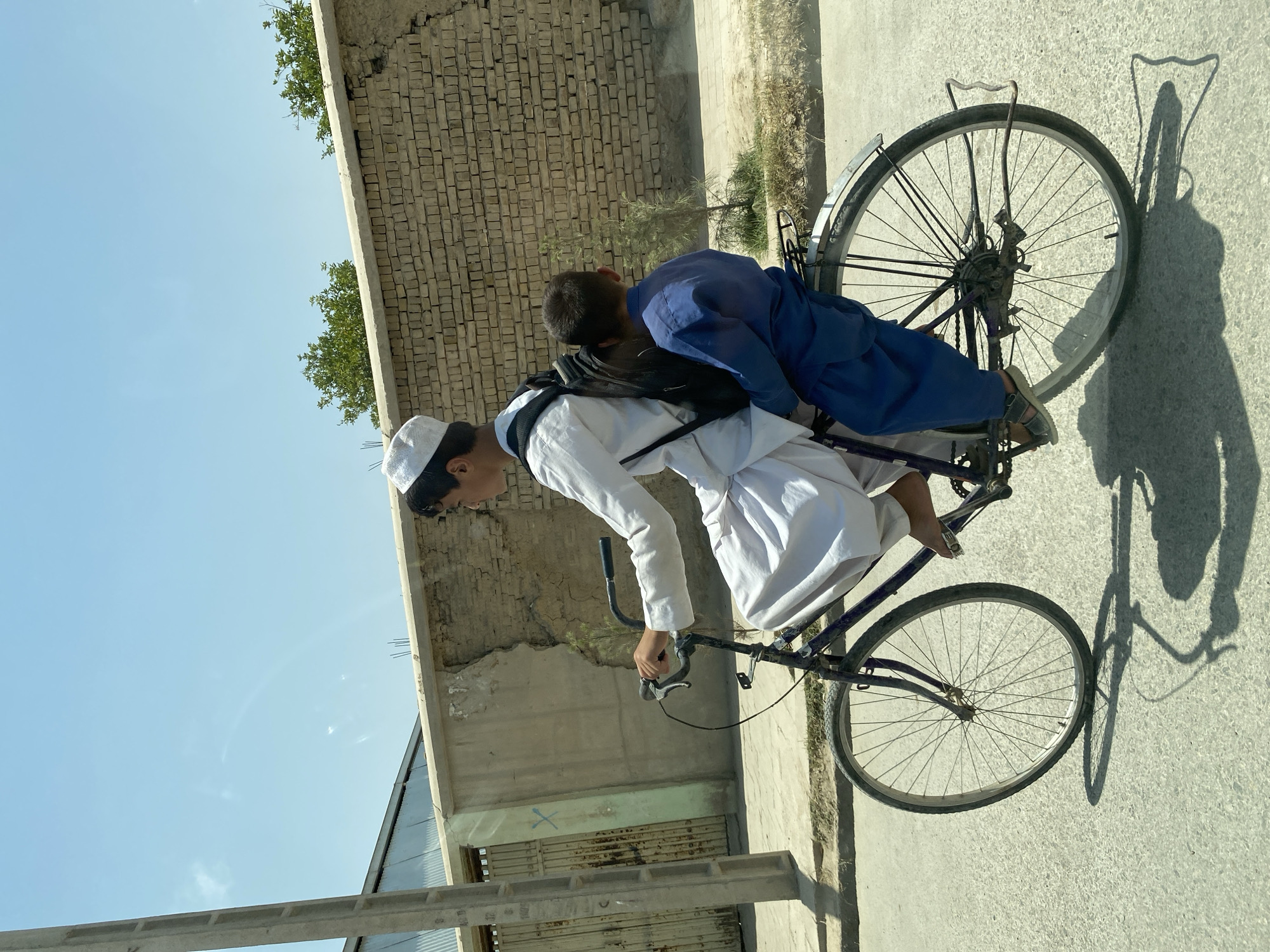 Sharing a bicycle on a paved Kandahar street