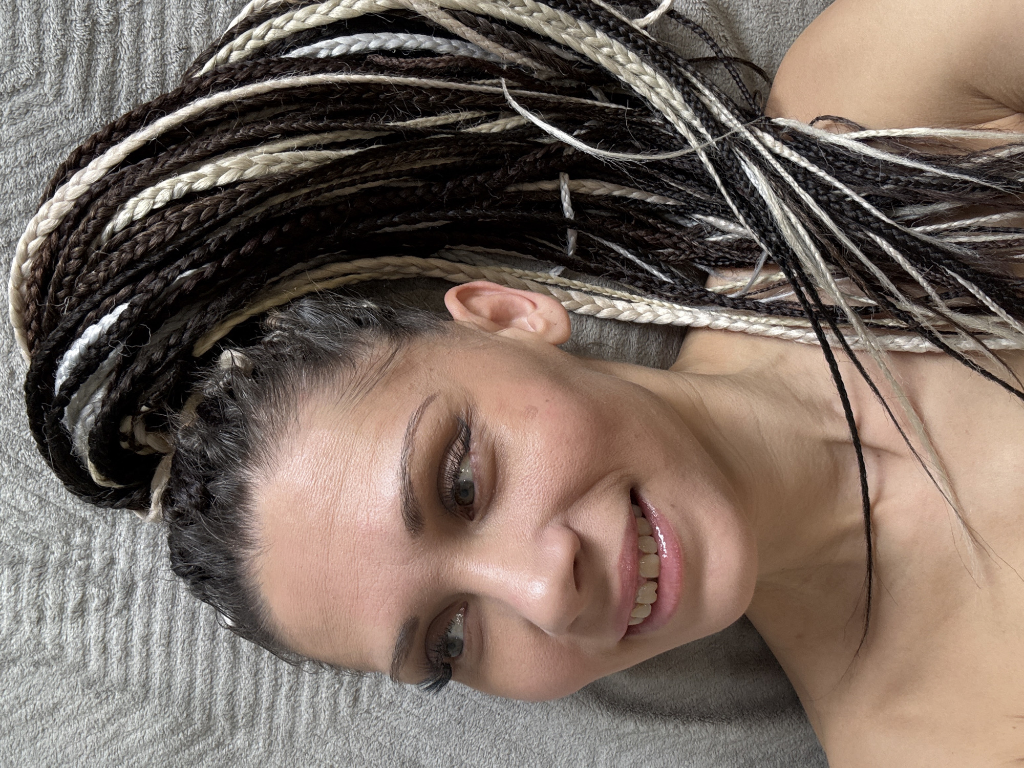 Person with braided hair rests on fabric surfaces
