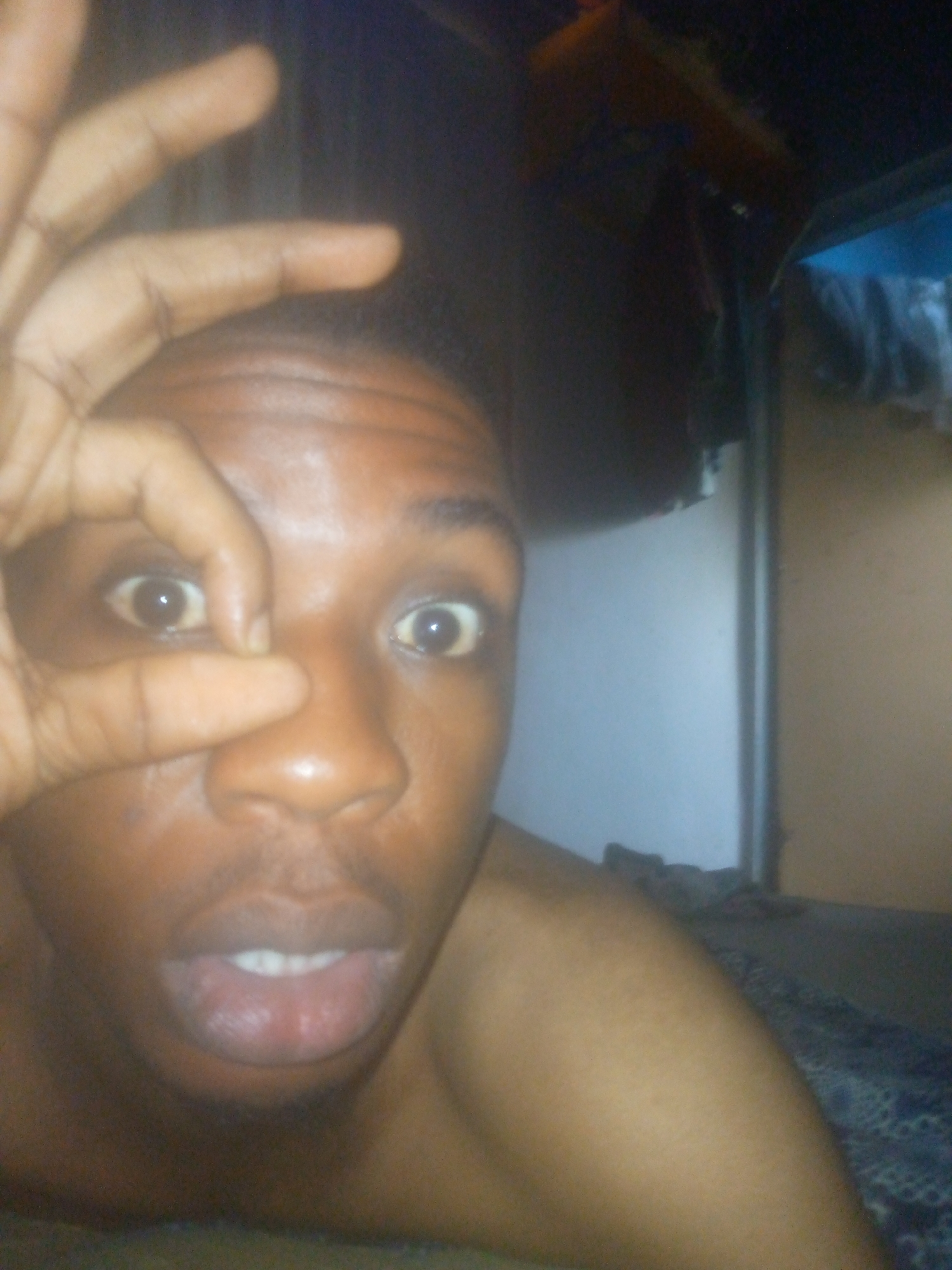 Person photographed making OK gesture over eye at location