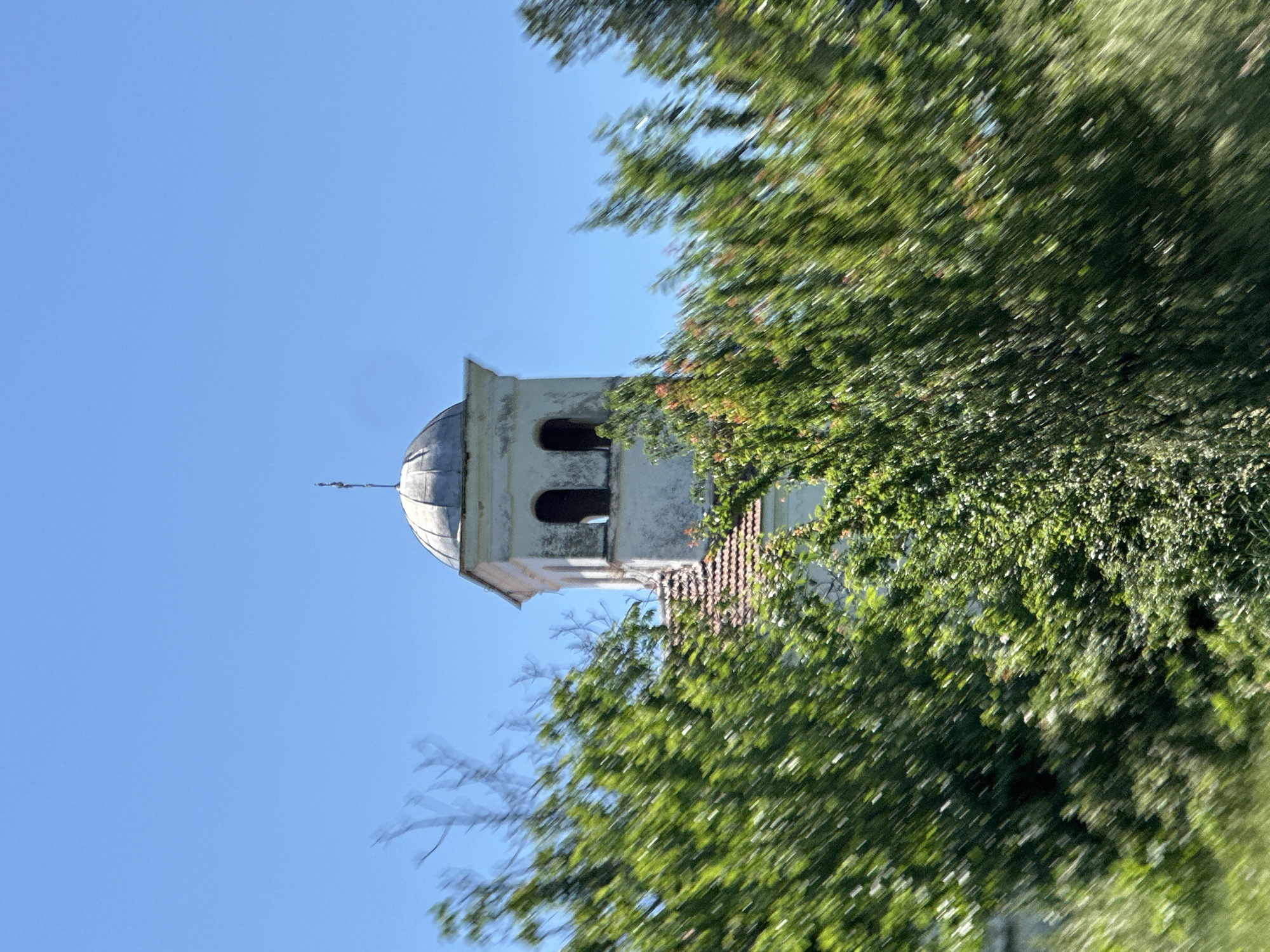 Church tower photographed through foliage in Slavyani, Bulgaria