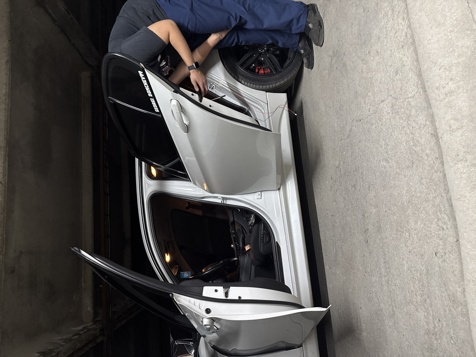 Two people tend to silver car in Sliven garage