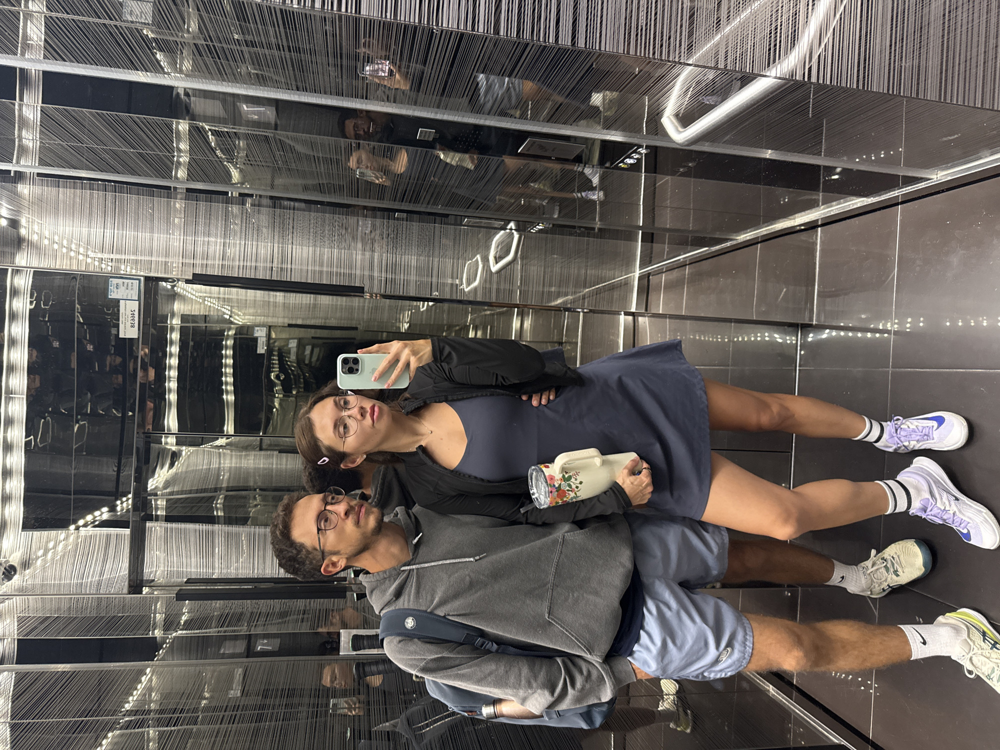 Two young adults take elevator mirror selfie in Tel Aviv