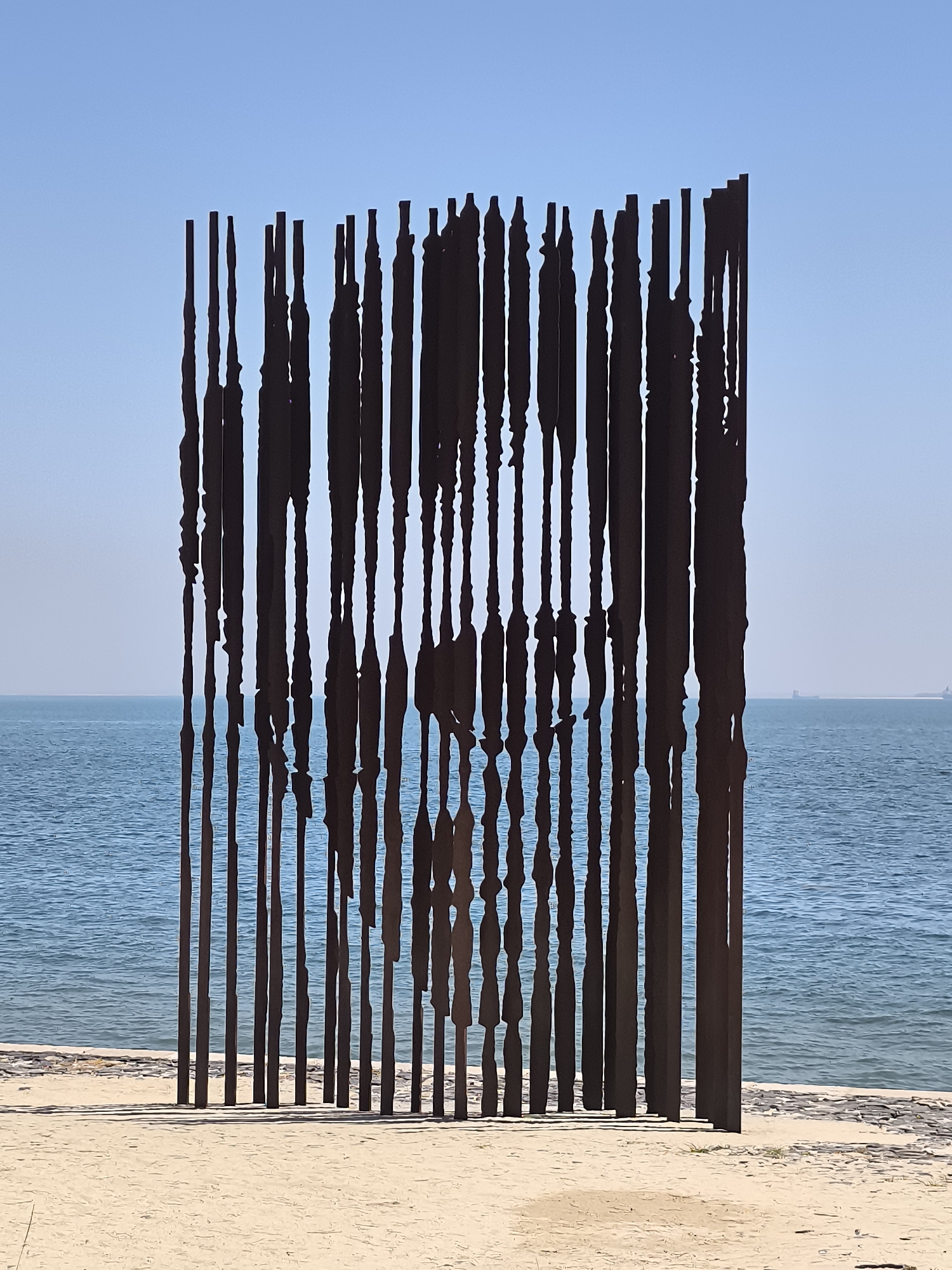 Metal beach sculpture and sailboats on the Setúbal coast