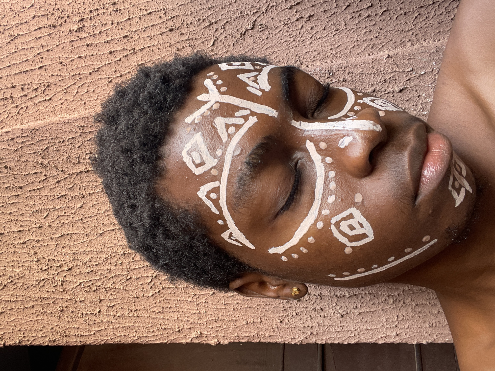 Person with tribal face paint rests in Nkpor, Nigeria