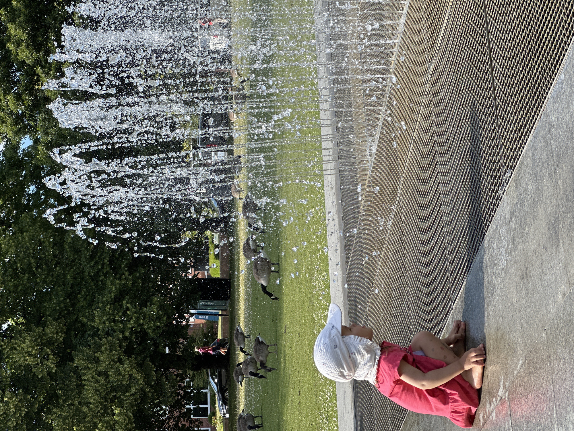 Kids cool off at a Kiel park fountain on a sunny afternoon