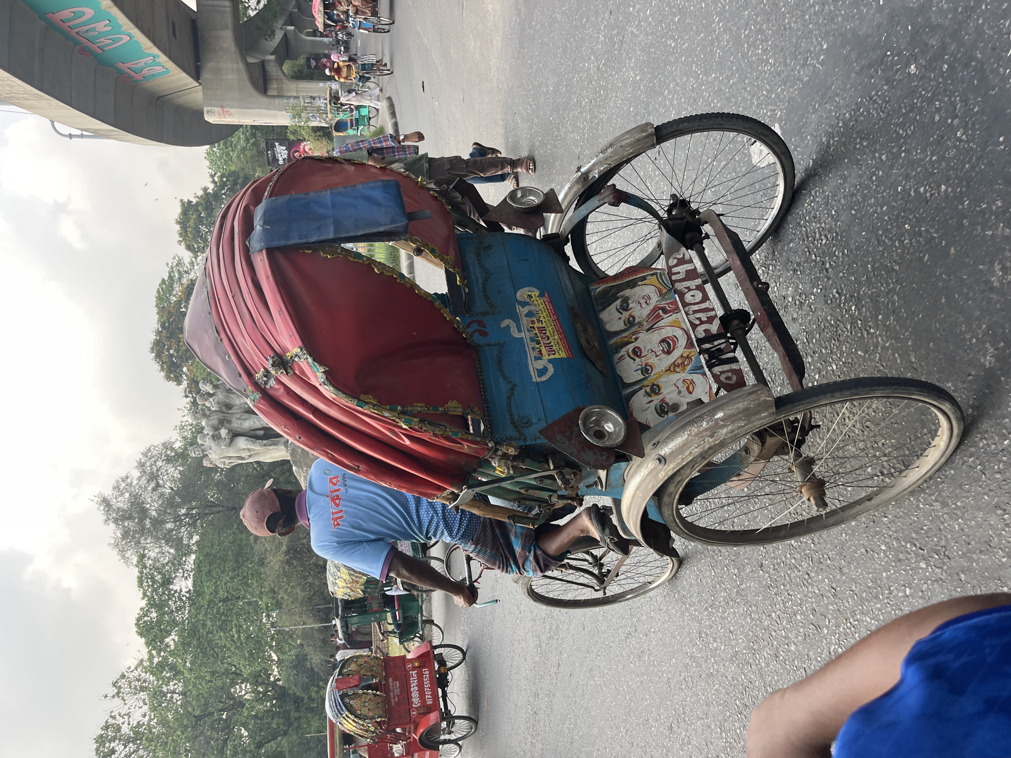 Rickshaws and decorated van share busy Dhaka street