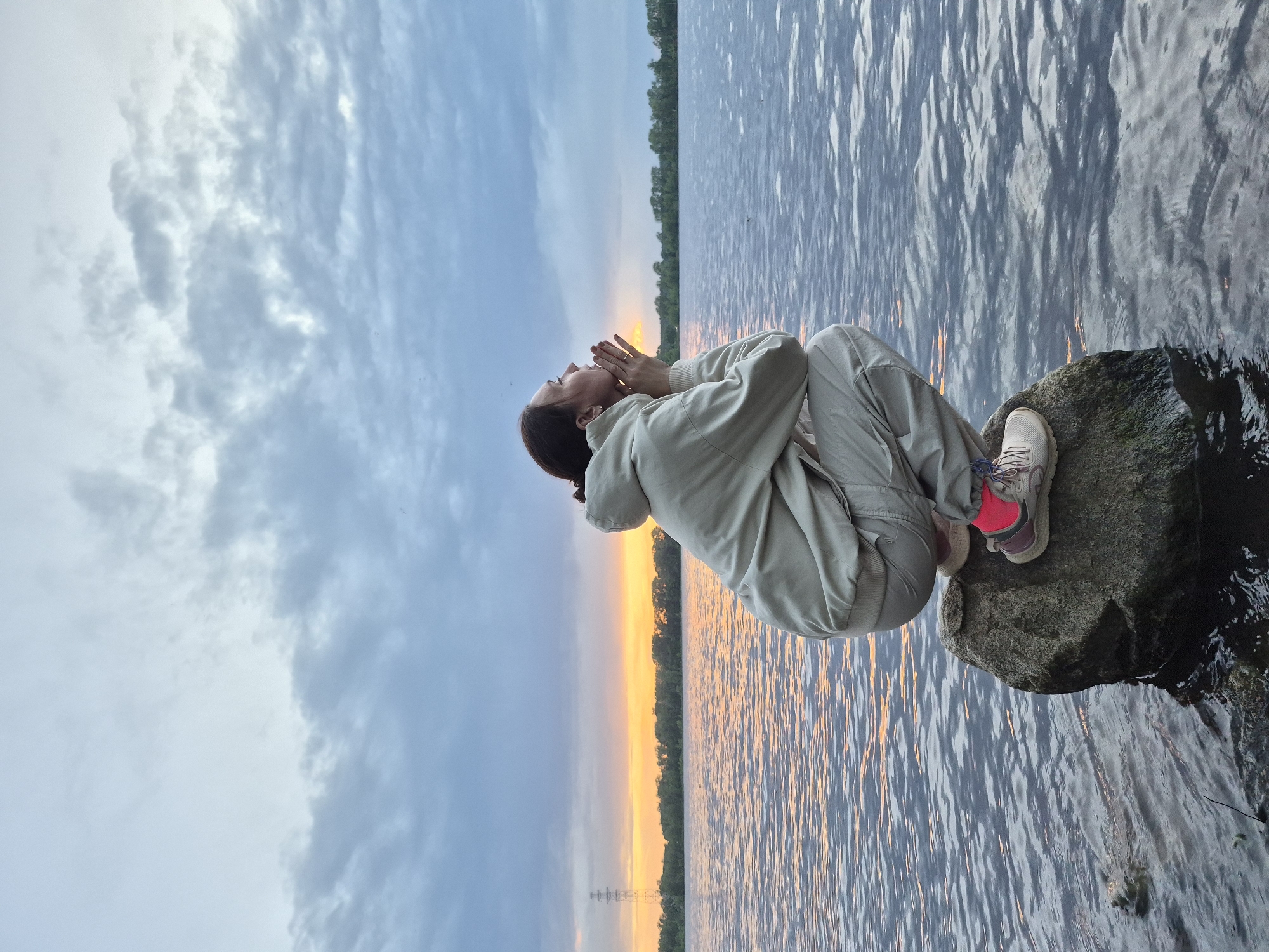 Woman enjoys sunset moment by water's edge
