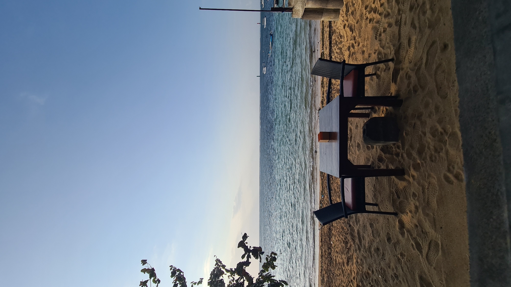 Denpasar beachfront at golden hour, people and boats