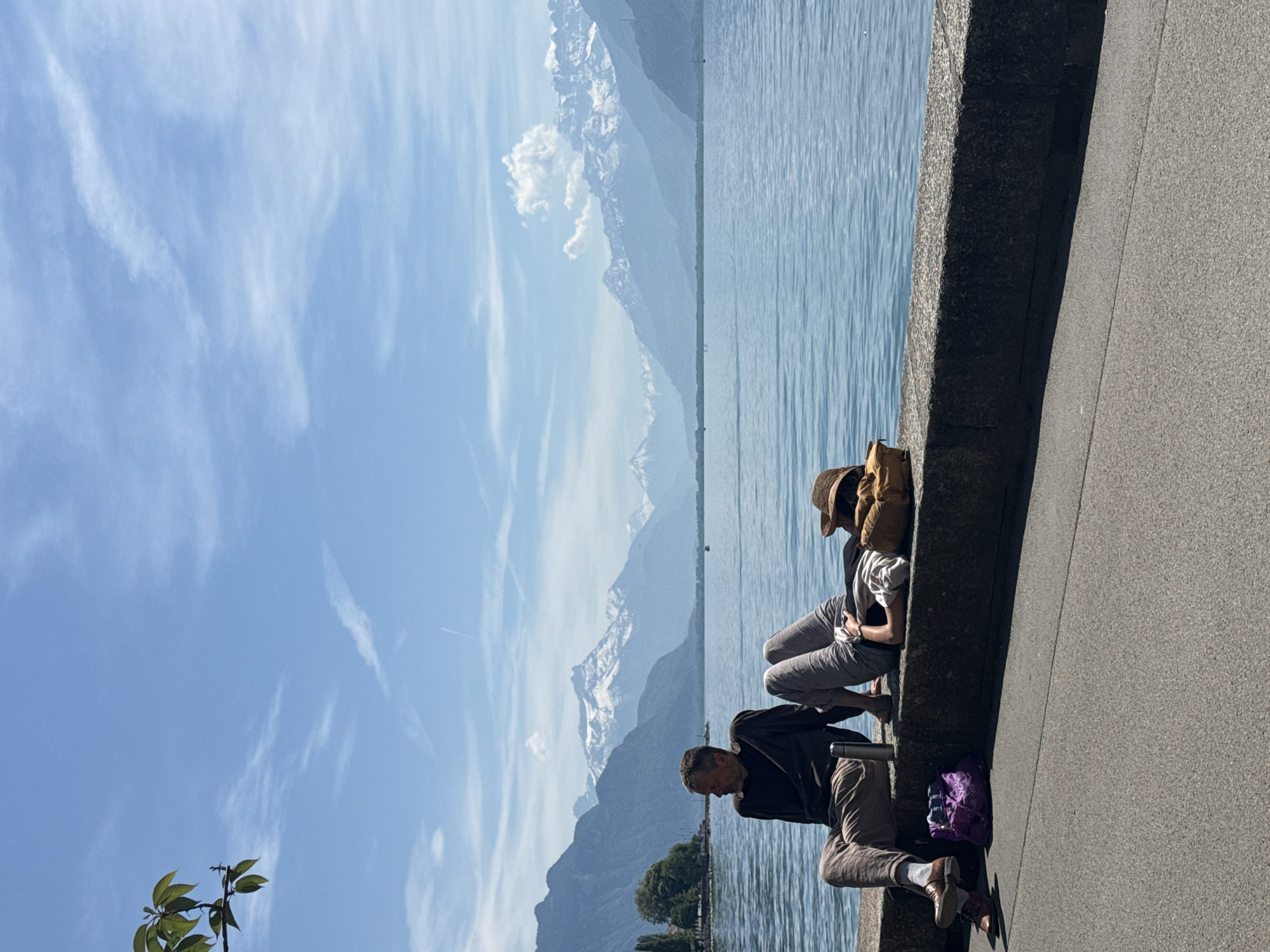 Two people sit by Lake Geneva in Vevey