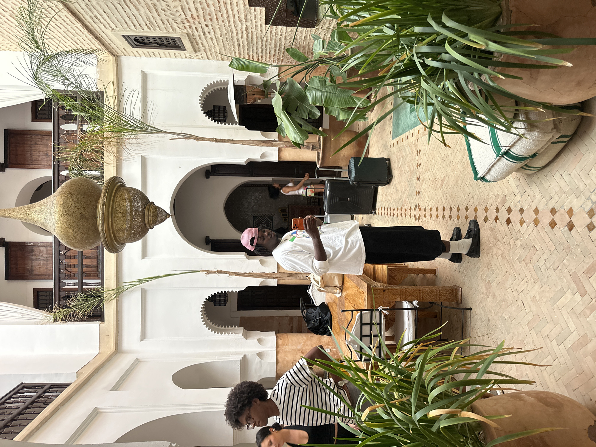 Man checks phone in courtyard garden, Marrakesh