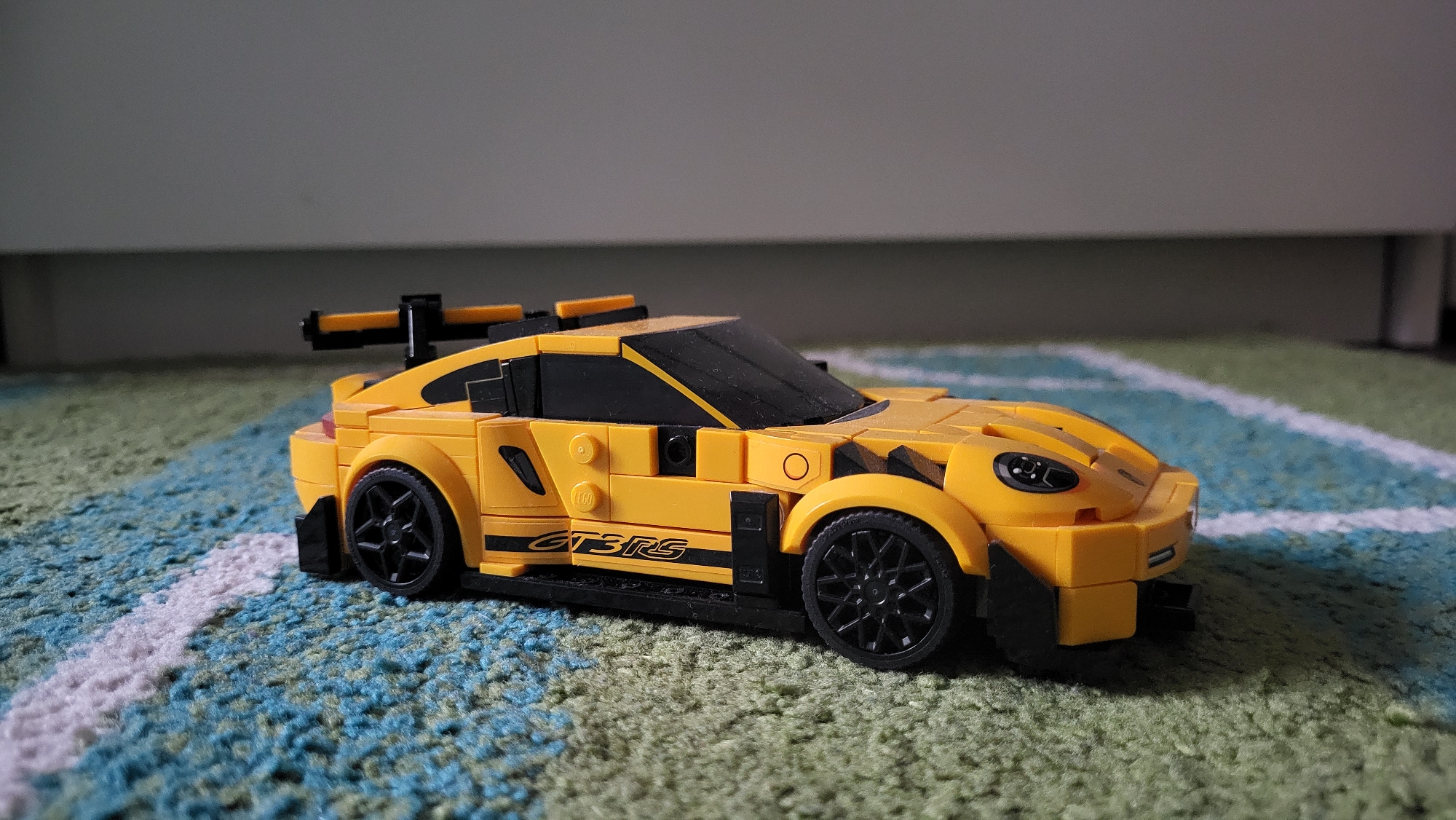 Yellow Lego Porsche model displayed on patterned carpet in Sofia