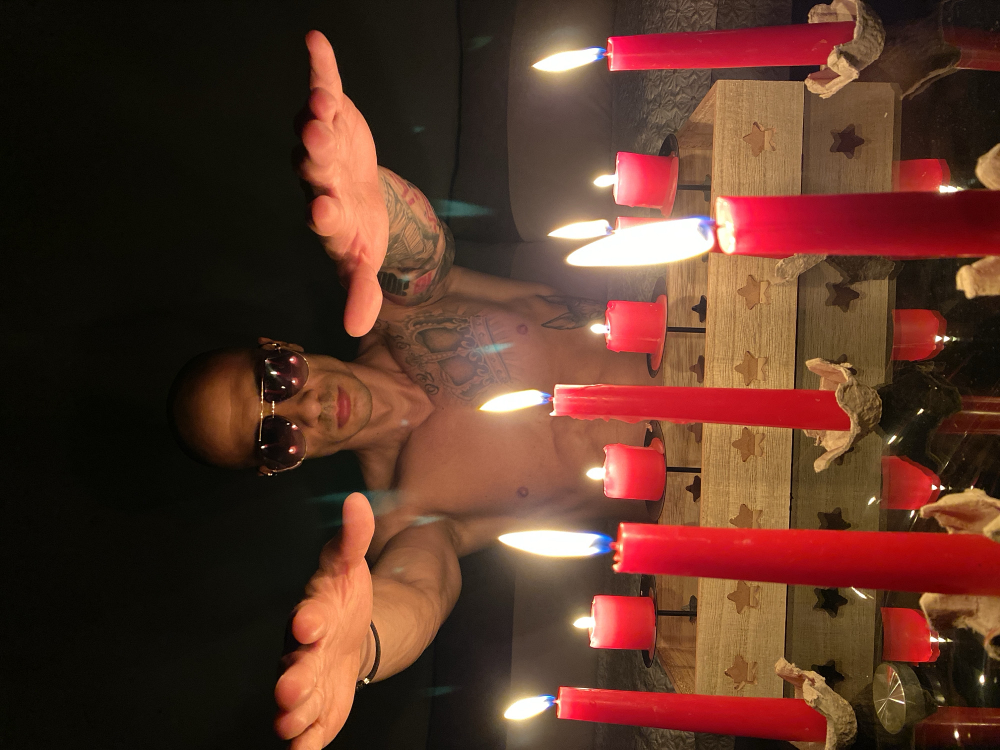 Tattooed man observed in candlelit scene in Pleven, Bulgaria
