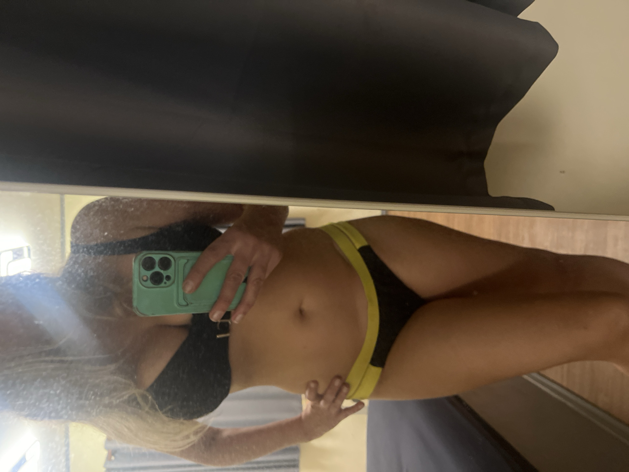 Mirror selfie in black and yellow bikini, indoor setting