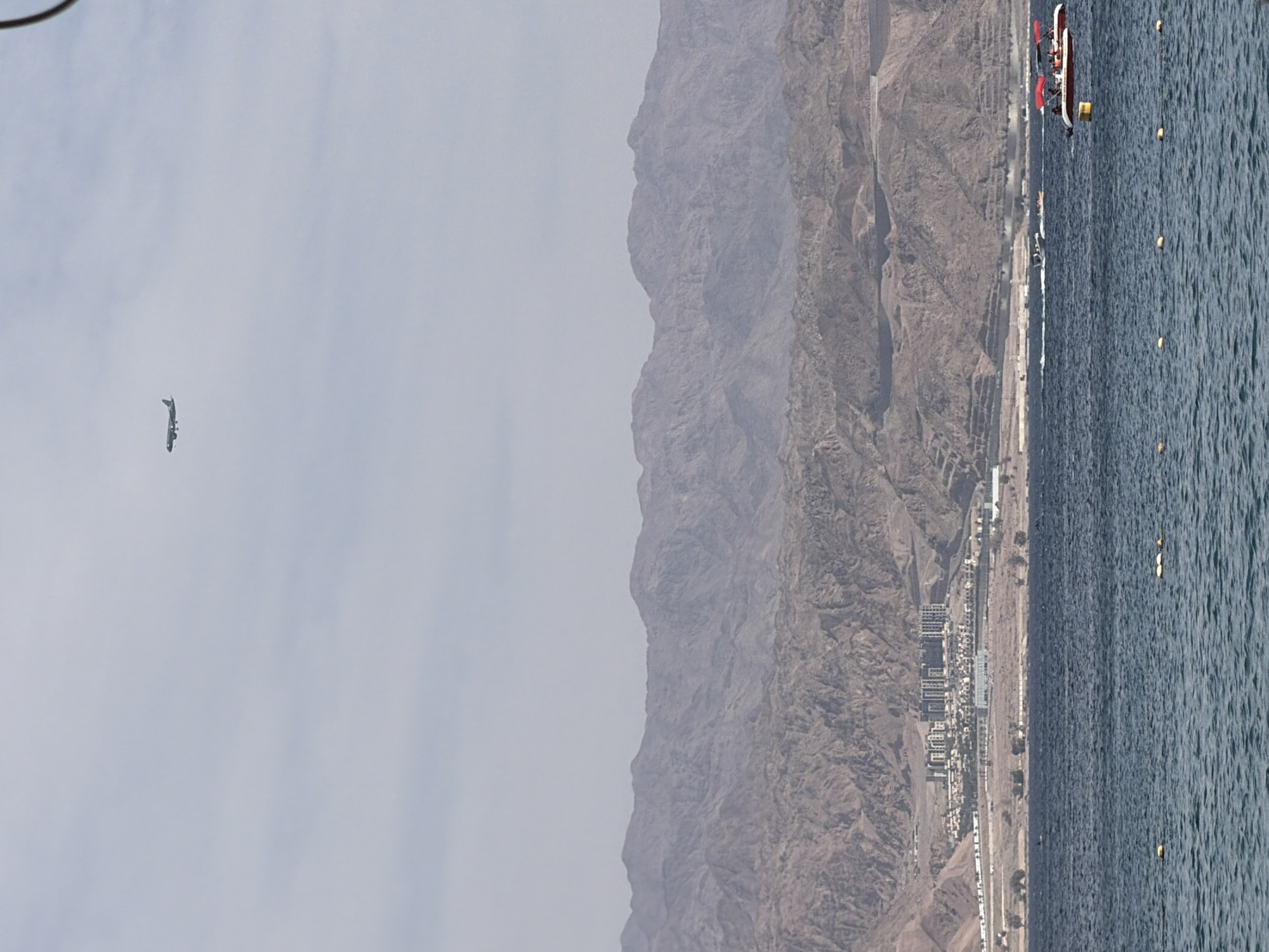 Boys paddleboard in Eilat waters amid mountain backdrop