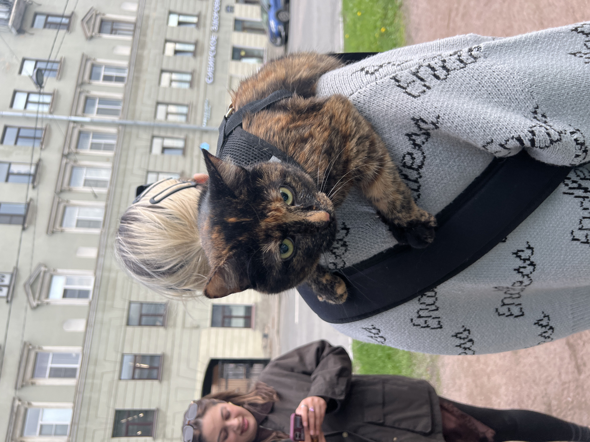 Woman carries harnessed cat on shoulder in Saint Petersburg square