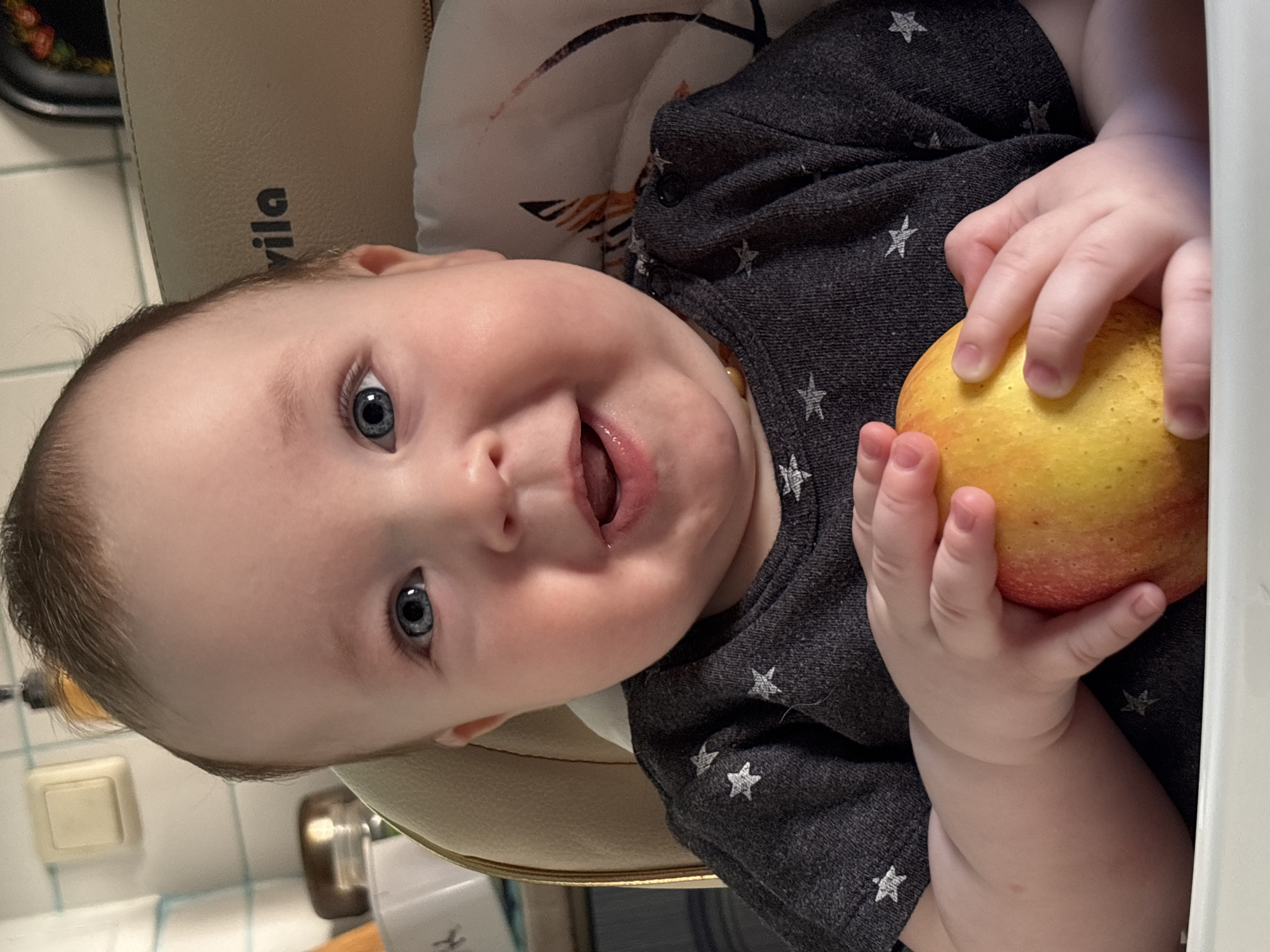 Baby holds apple during early morning feeding in Russia