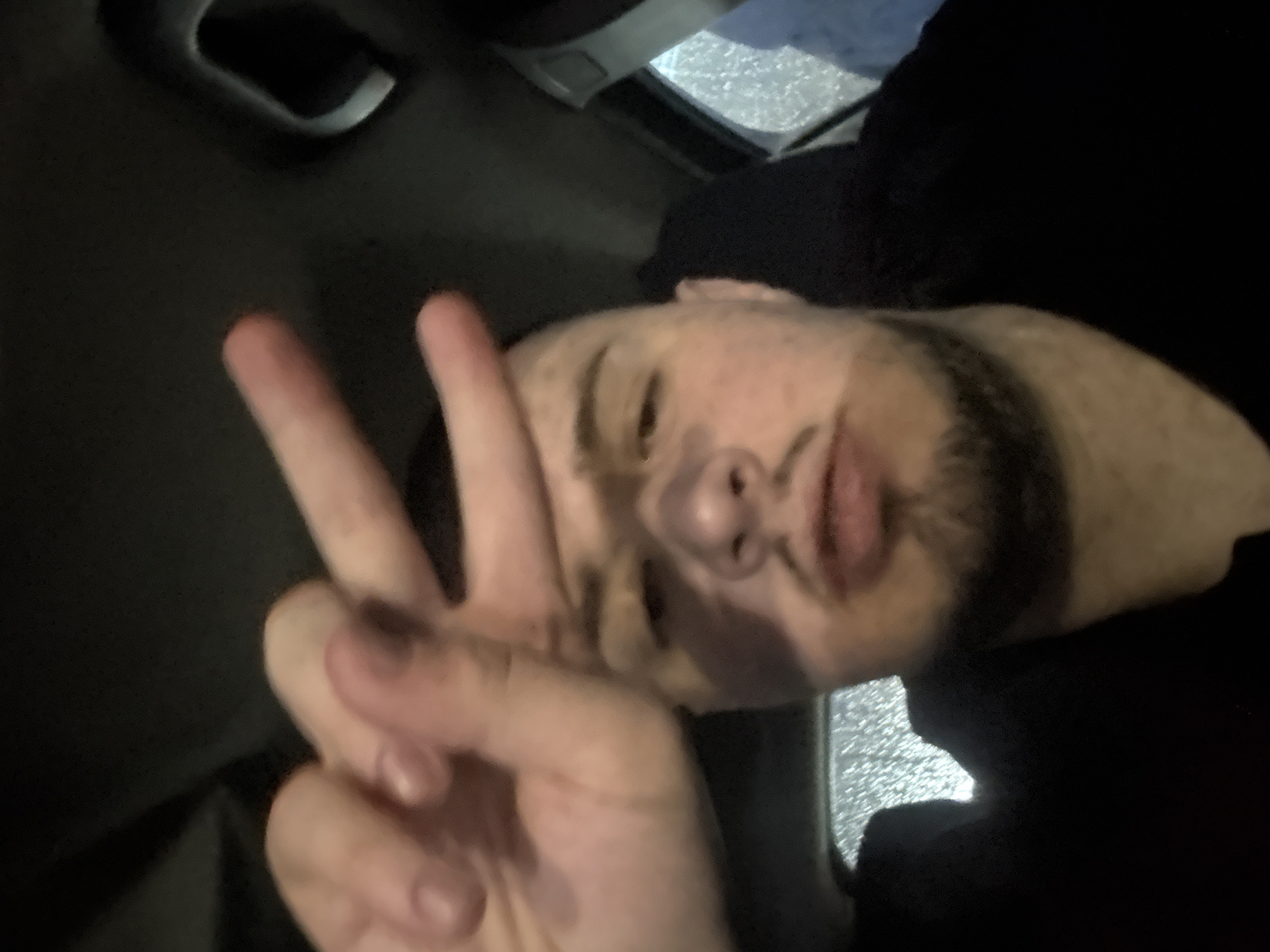 Man makes peace sign in car during rain