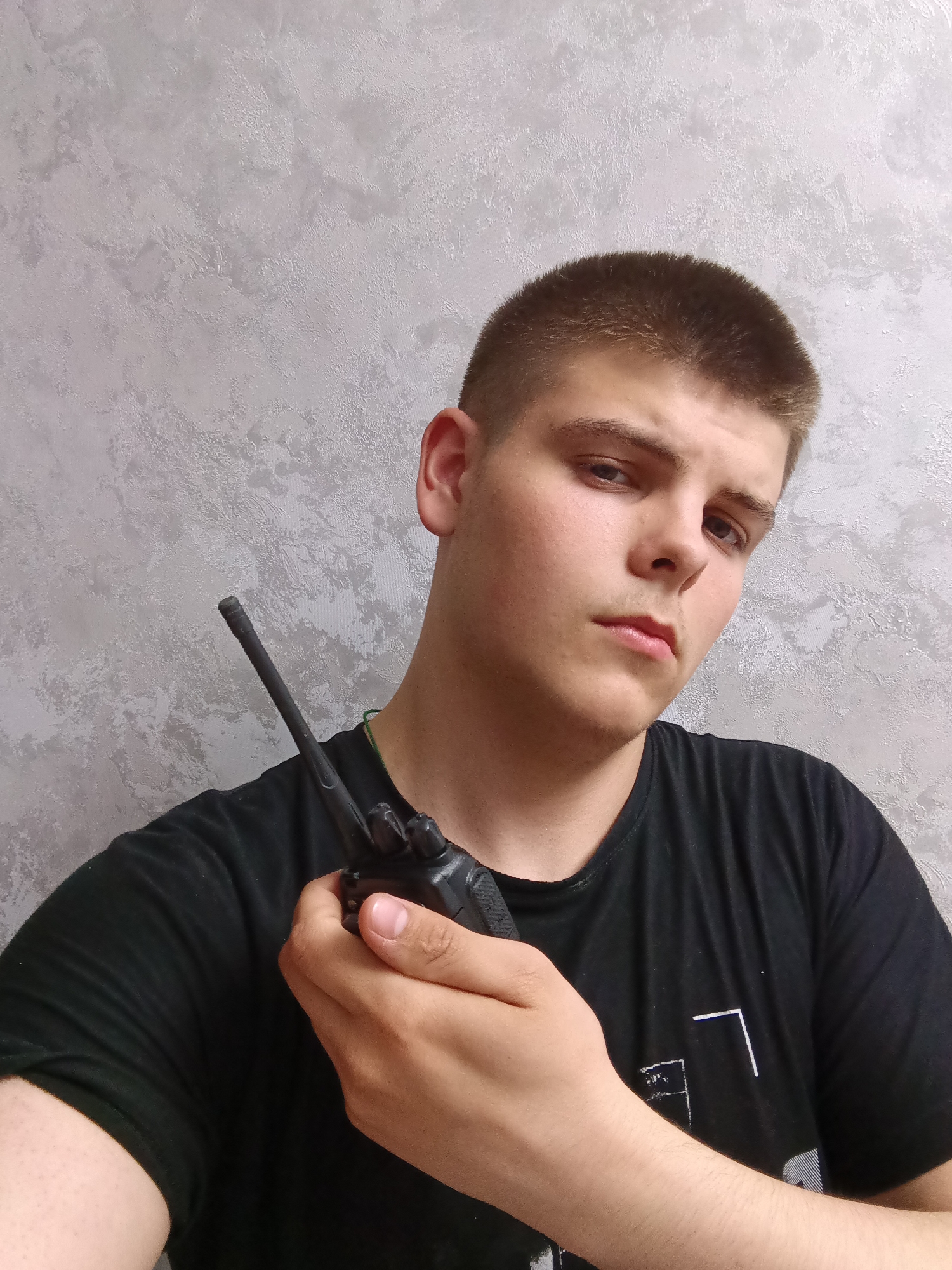 Young man poses with walkie-talkie, speaker in Russian indoor setting