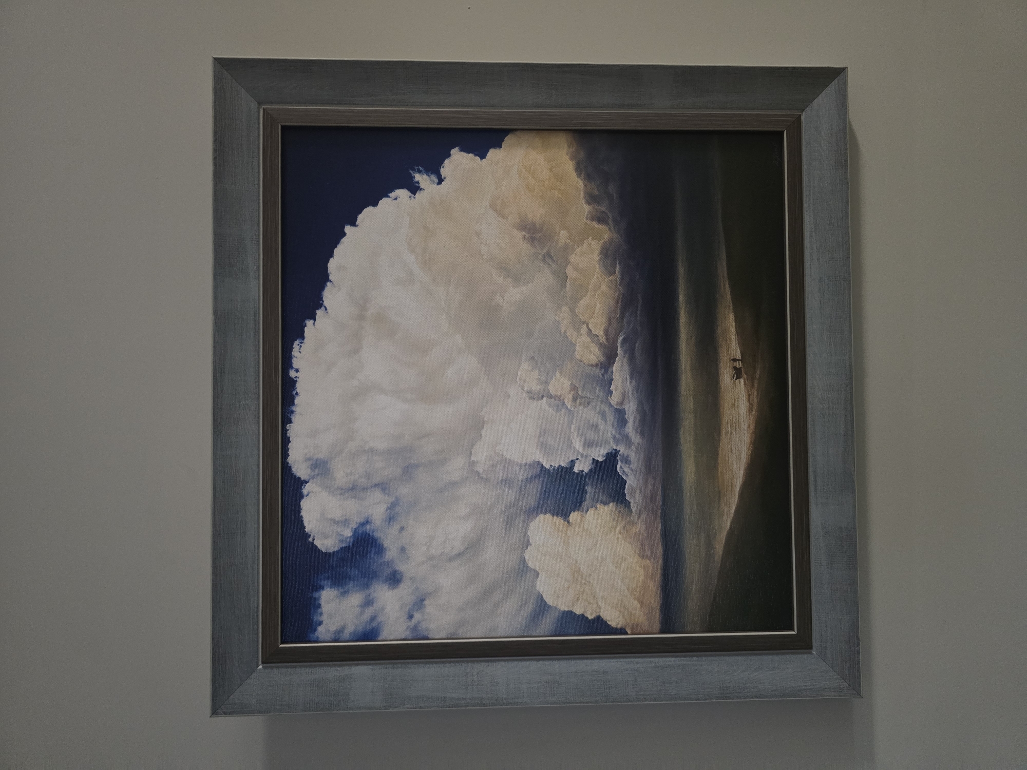 Framed cloud painting observed on gray wall