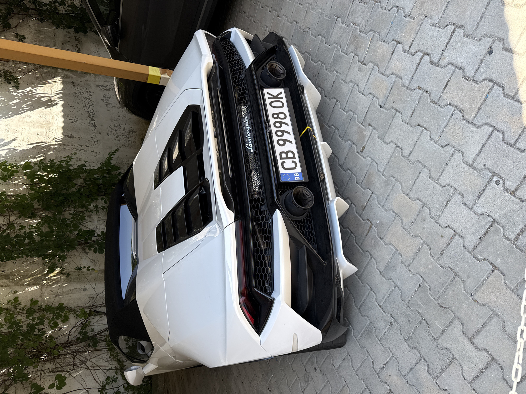 Yellow Urus and white Huracán parked together under a carport