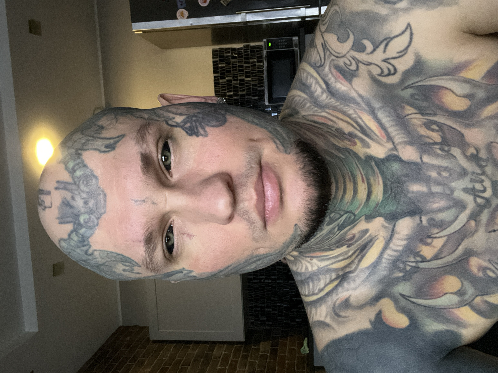 Tattooed man poses for kitchen photograph in Kudrovo