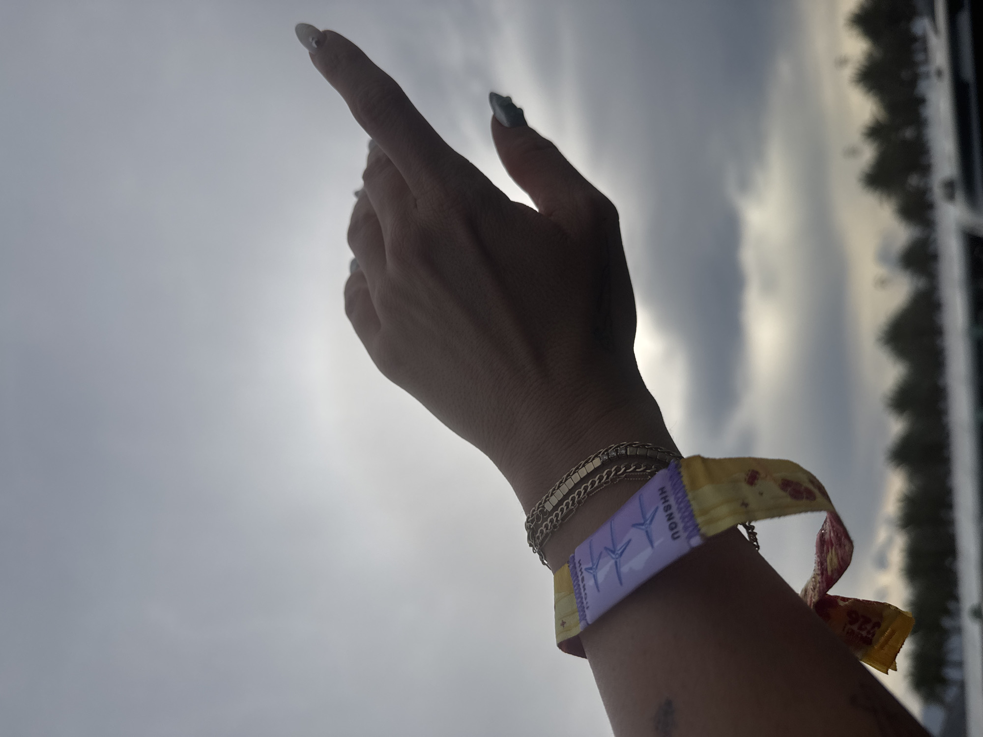 Person points to sky in Indian Wells wearing colorful wristband